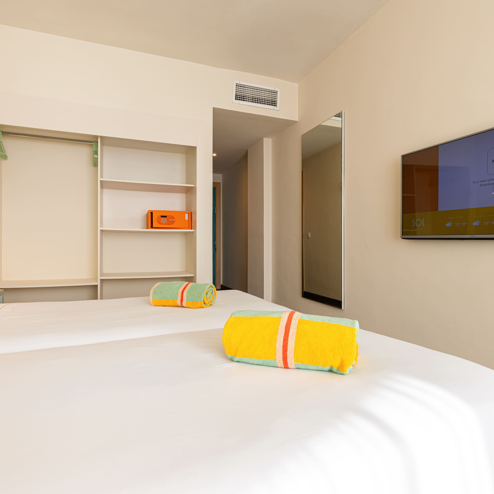 Habitación de hotel Meliá con dos camas, TV, toallas de playa y caja fuerte.