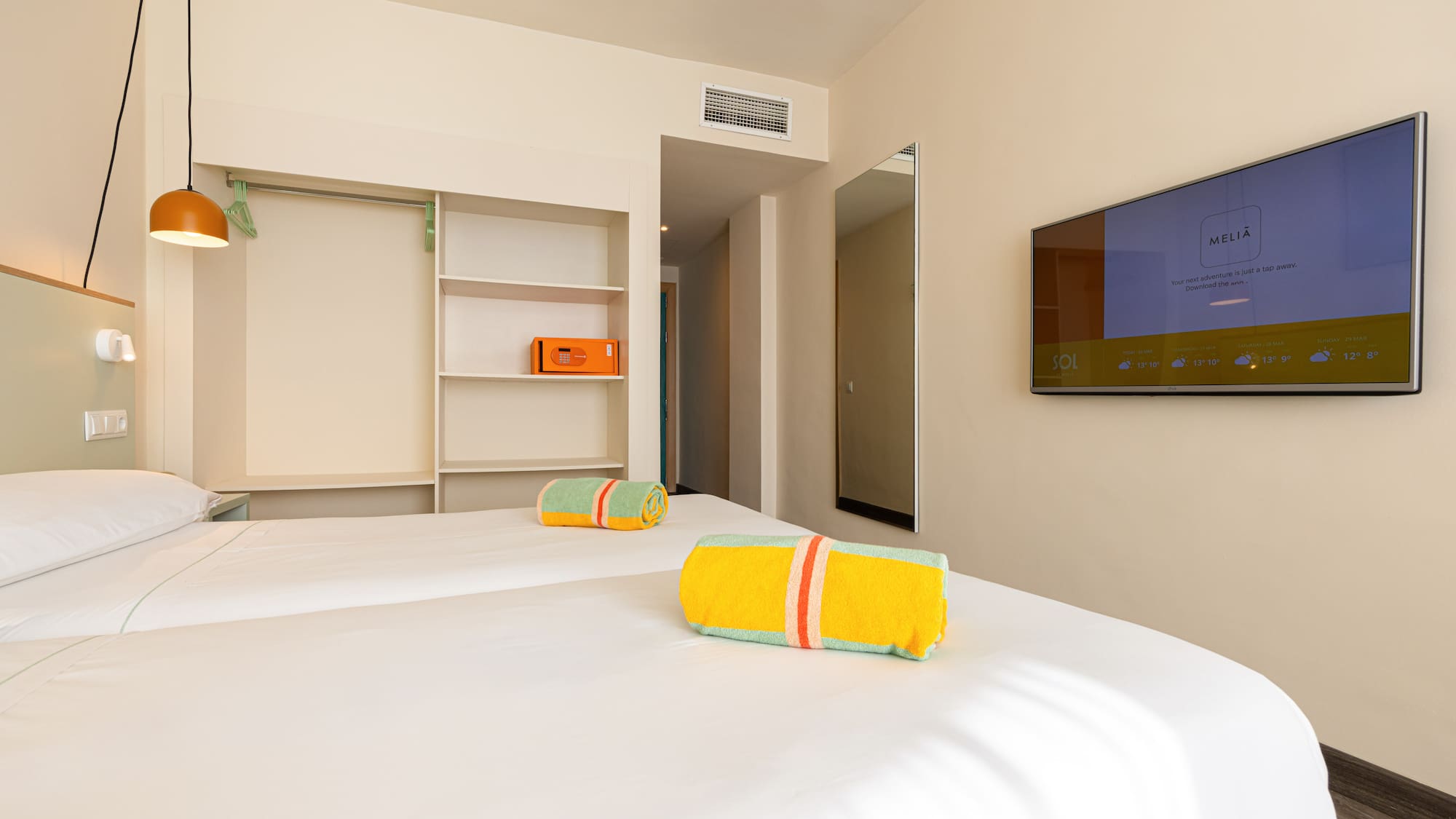 Habitación de hotel Meliá con dos camas, TV, toallas de playa y caja fuerte.