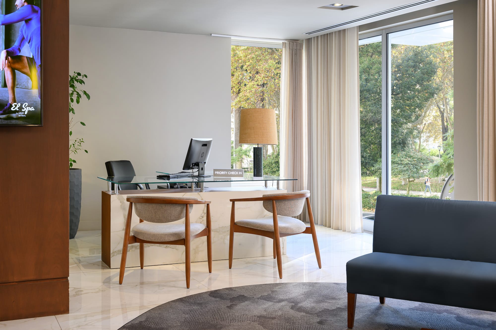 Spa hotel reception with "Priority Check In" desk and garden view.