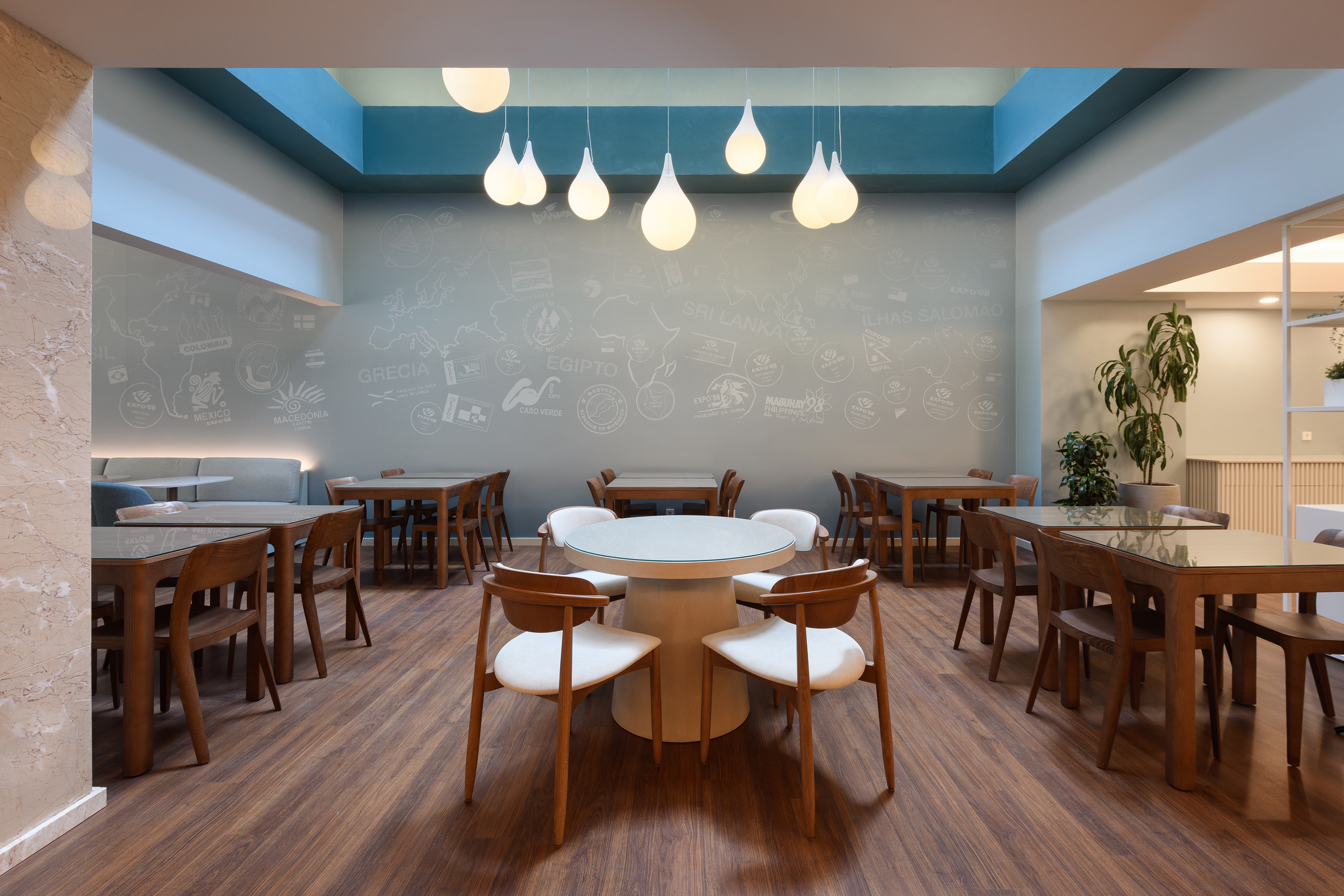 Modern cafe interior with wooden tables, pendant lights, and a world map wall mural.