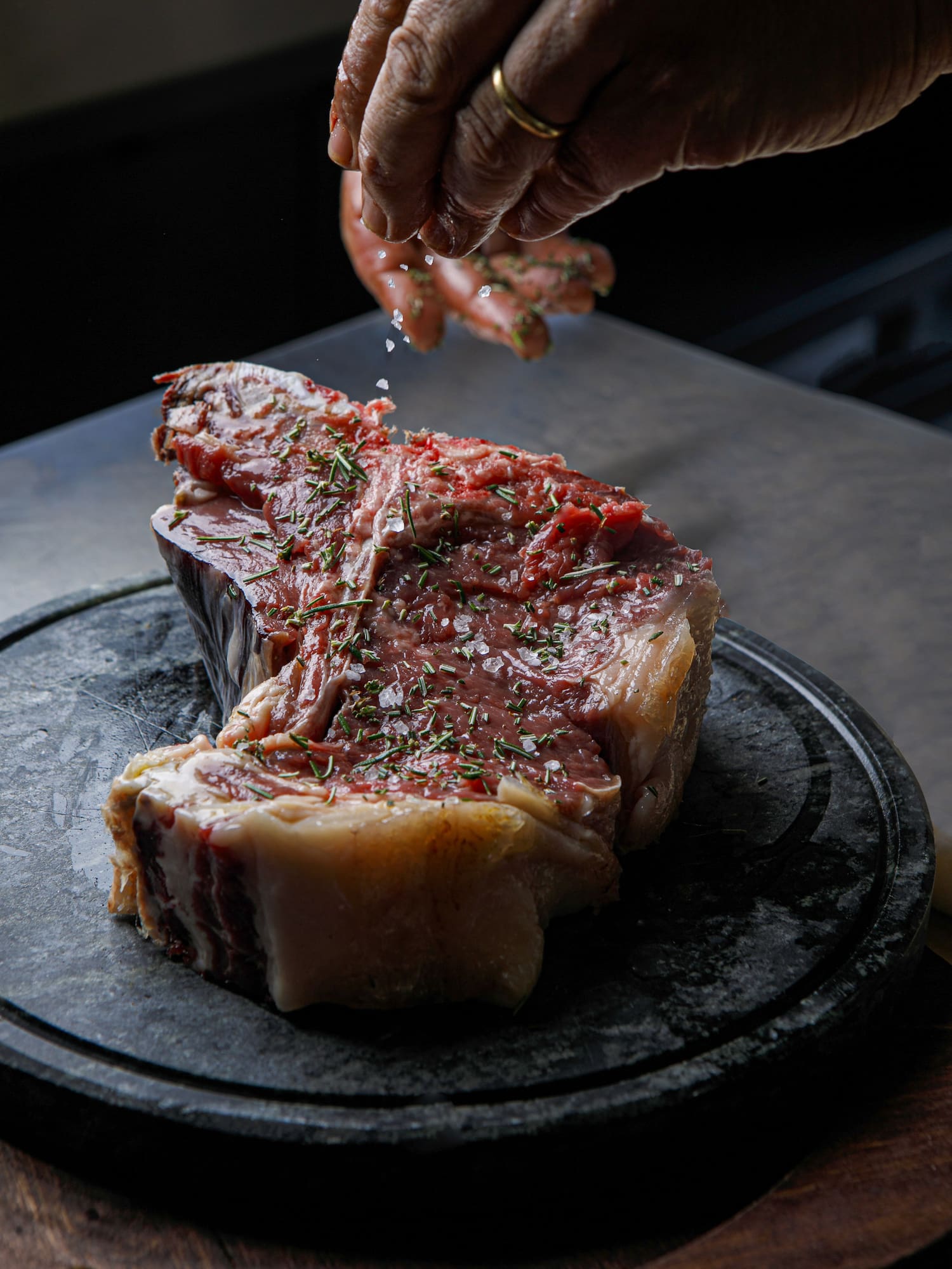 a hand sprinkling salt on a piece of meat