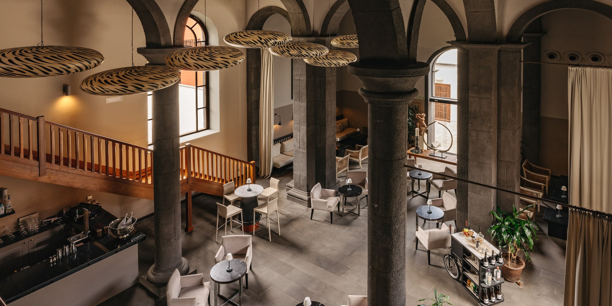 Spacious hotel lounge bar with stone arches, unique lighting, and cozy seating.