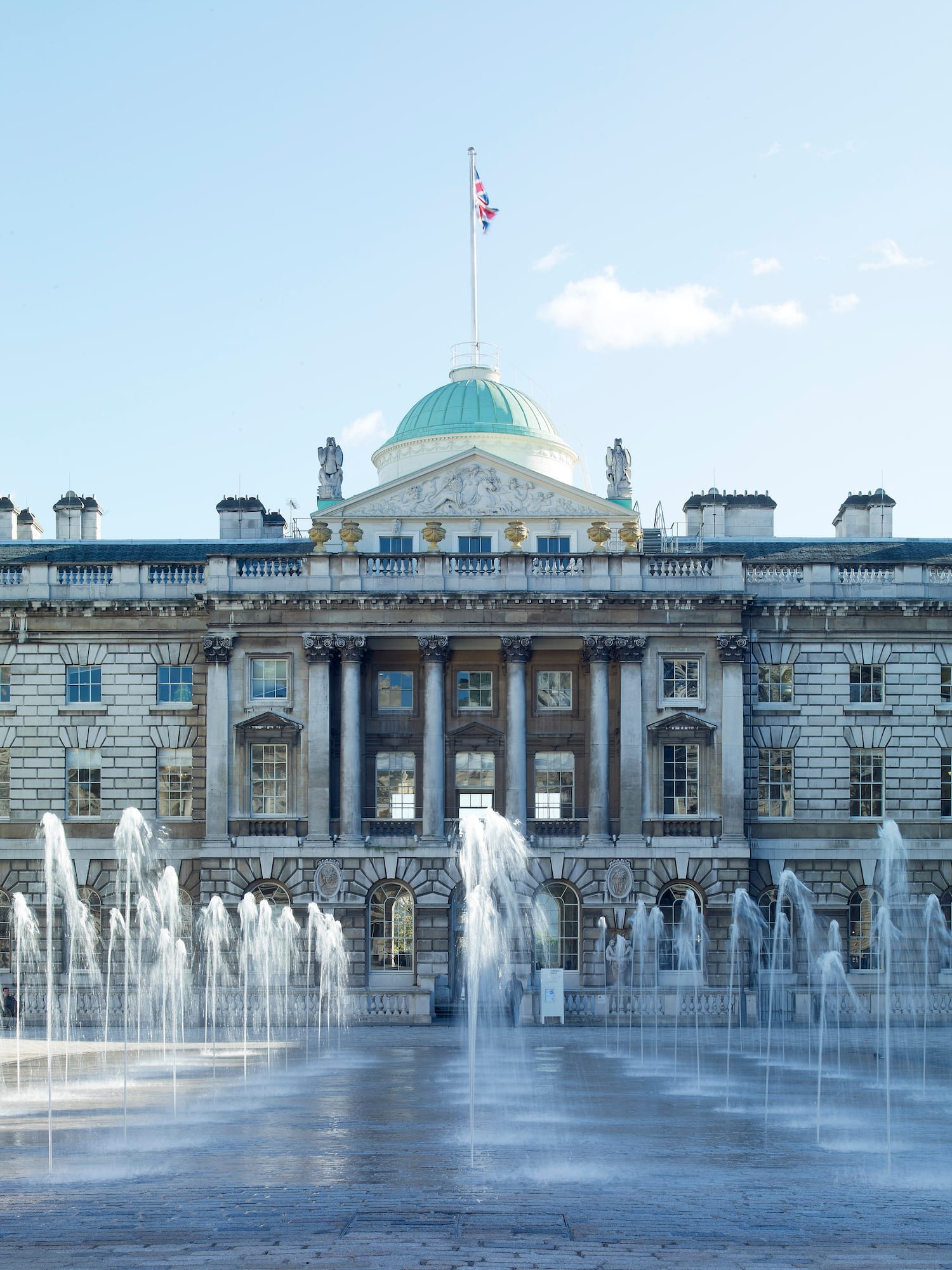 Somerset House, Londres, con fuentes de agua en primer plano y bandera británica.