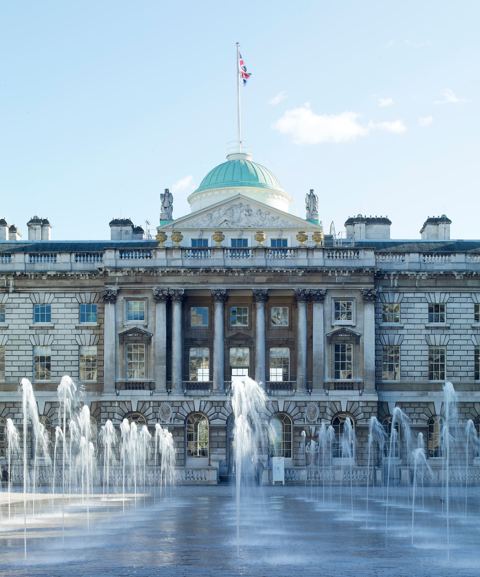 Somerset House, Londres, con fuentes de agua en primer plano y bandera británica.