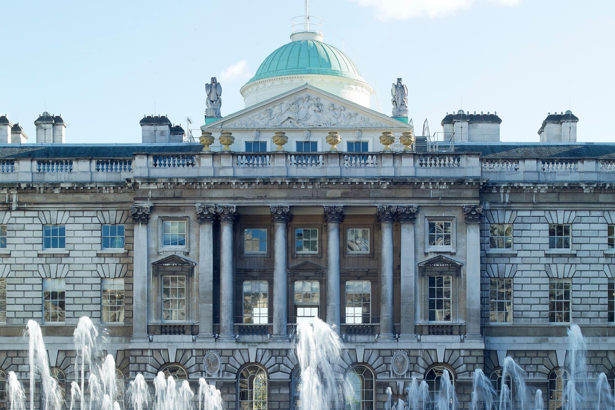 Somerset House, Londres, con fuentes de agua en primer plano y bandera británica.