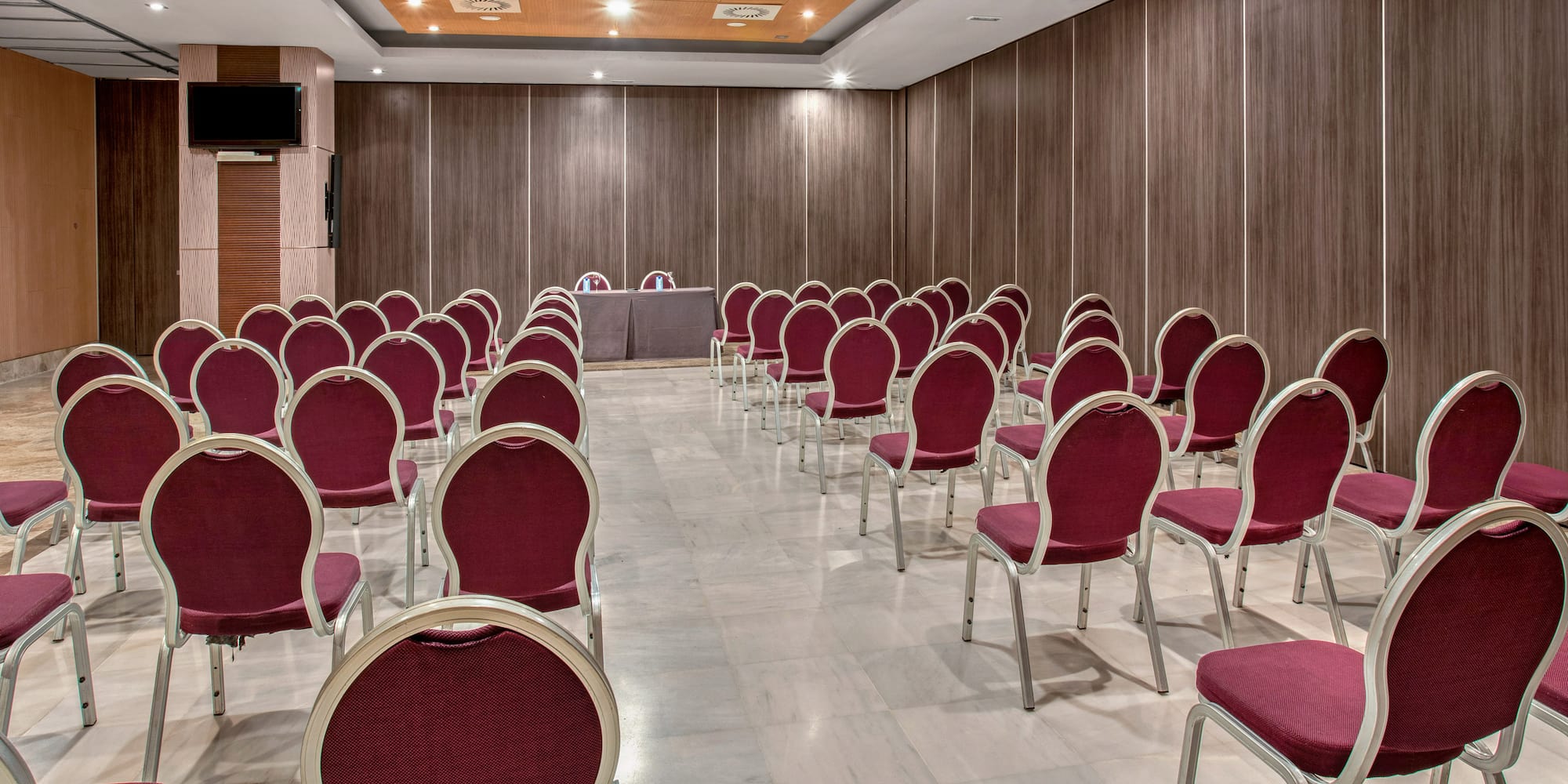 Modern meeting room with red chairs, wood walls, and screen for presentation.