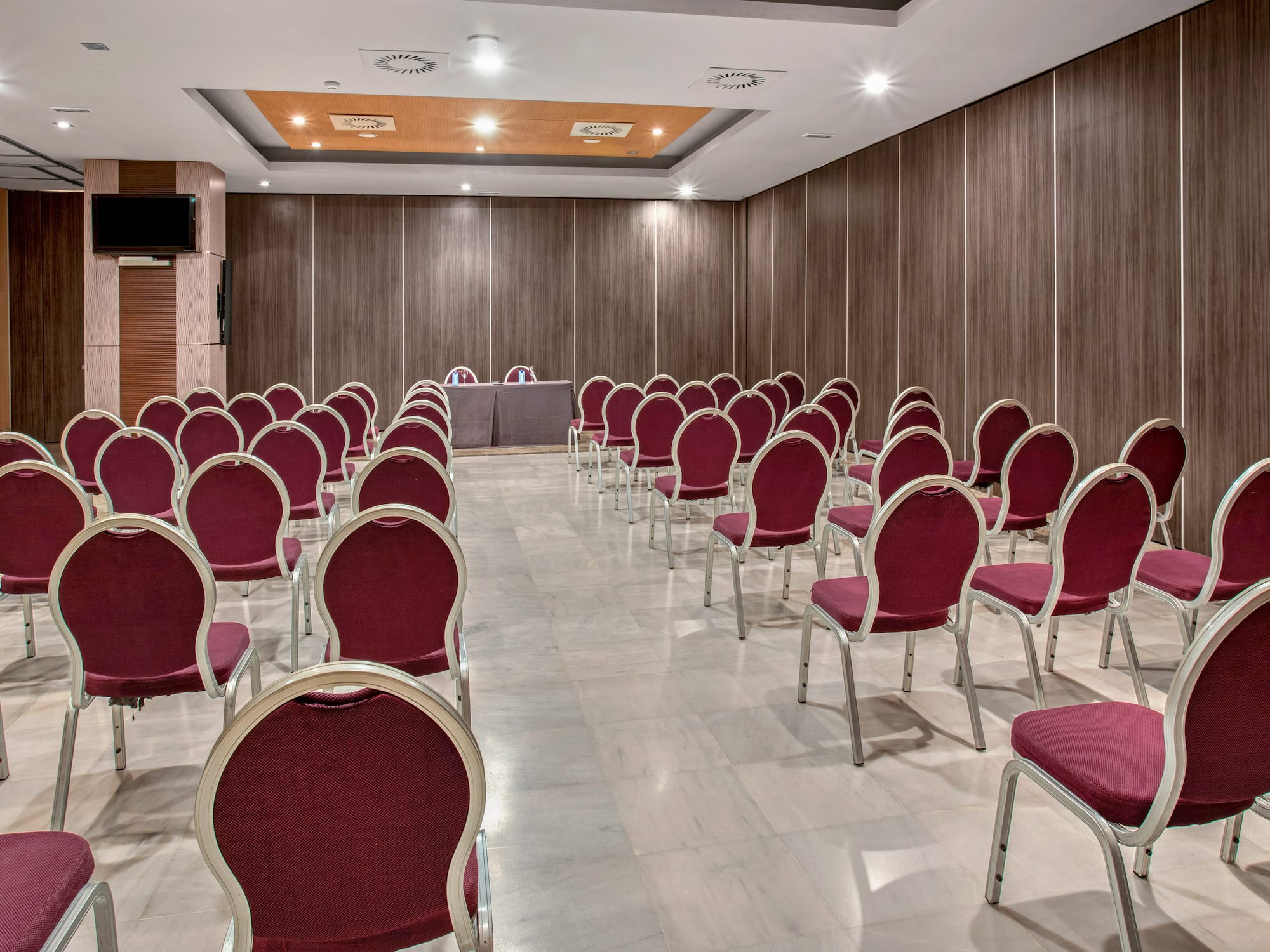 Modern conference room with red chairs, wood walls, and presentation screen.