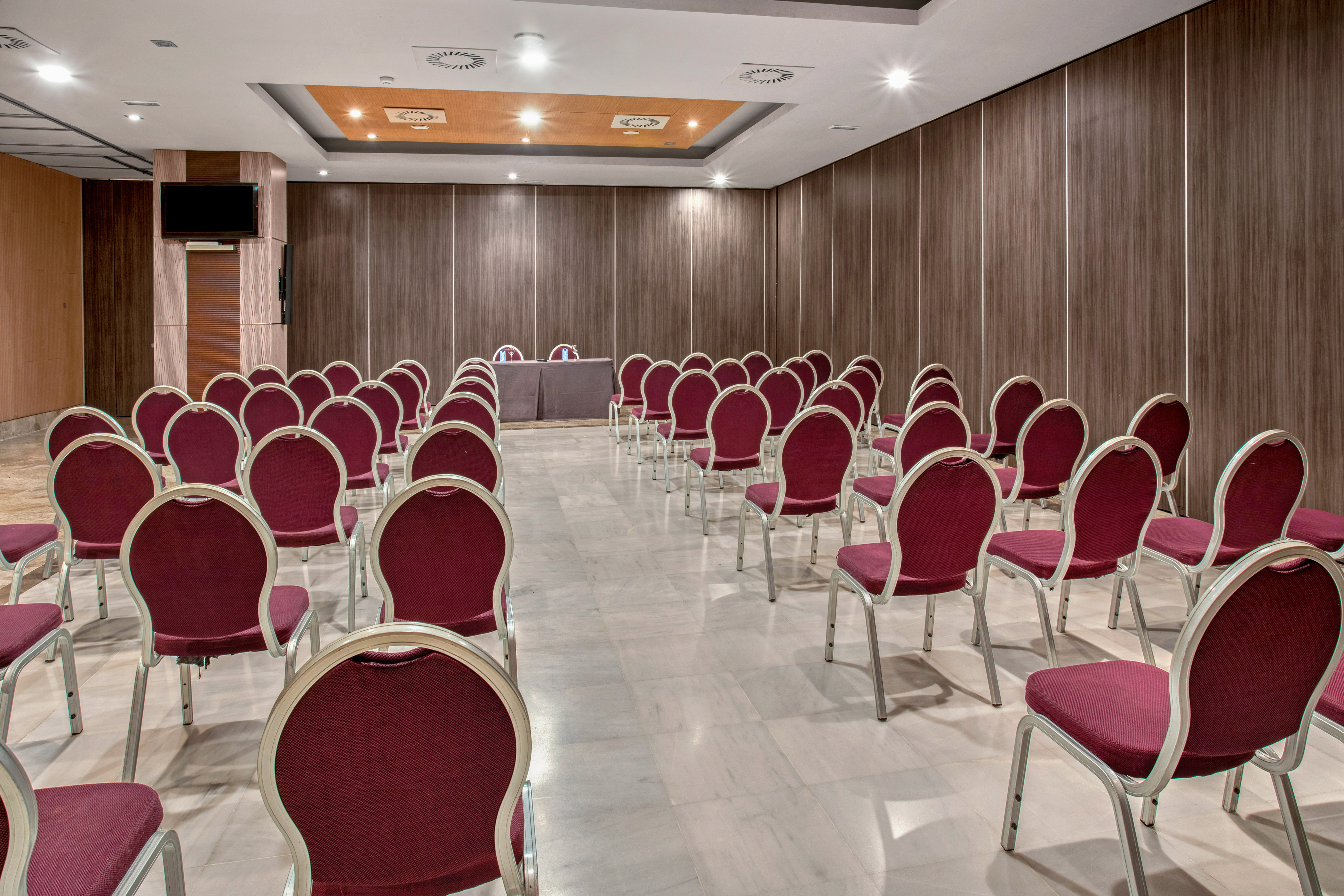 Modern conference room with red chairs, wood walls, and presentation screen.
