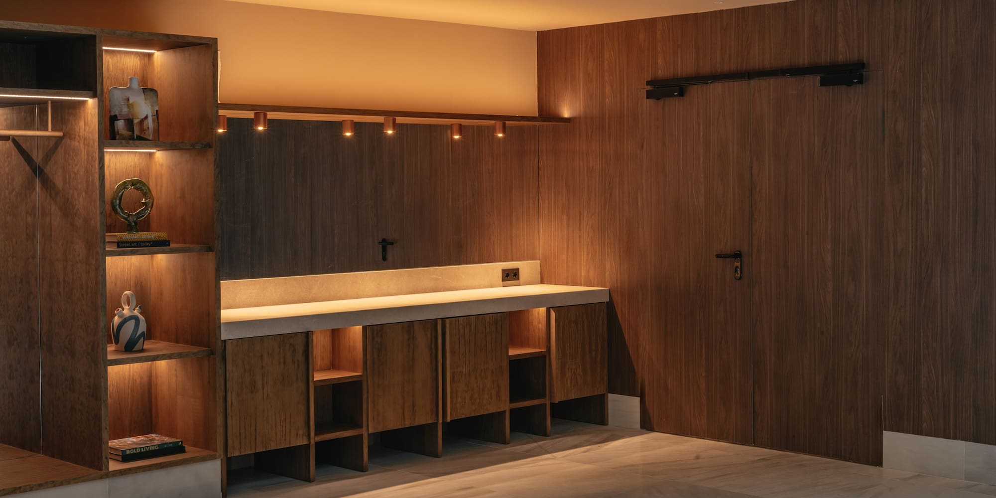 Modern interior with wood paneling, illuminated shelves, concrete counter, marble floor.