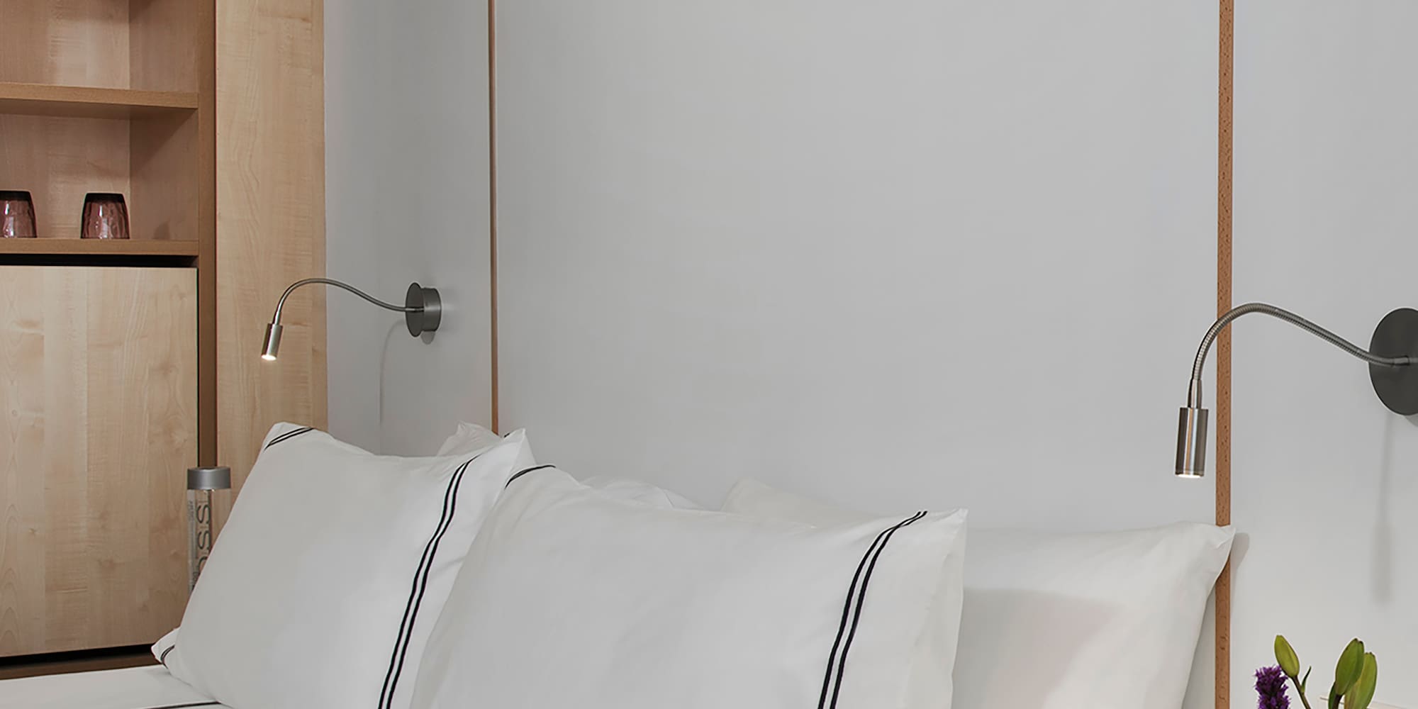 a bed with white sheets and a white nightstand