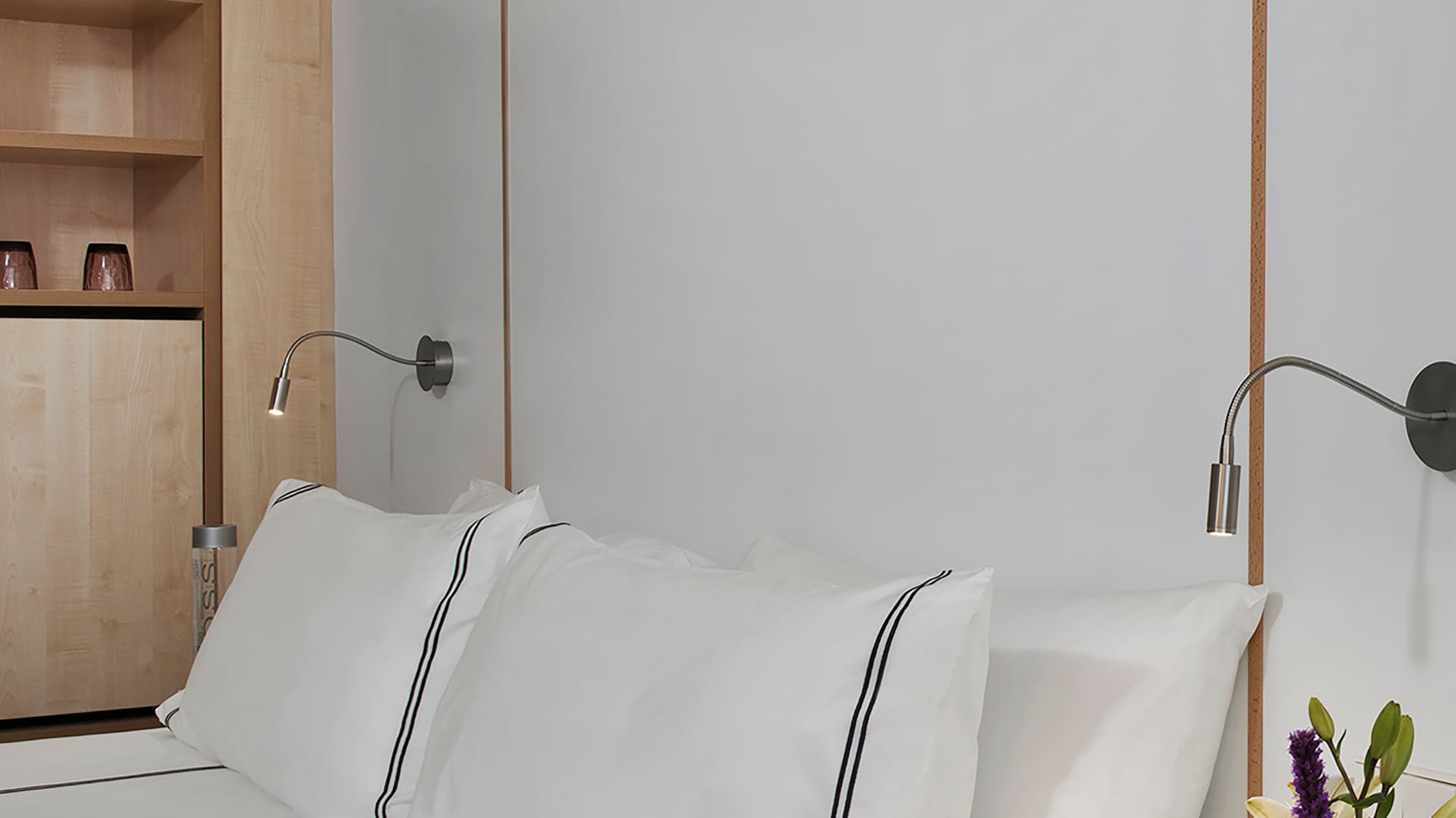 a bed with white sheets and a white nightstand