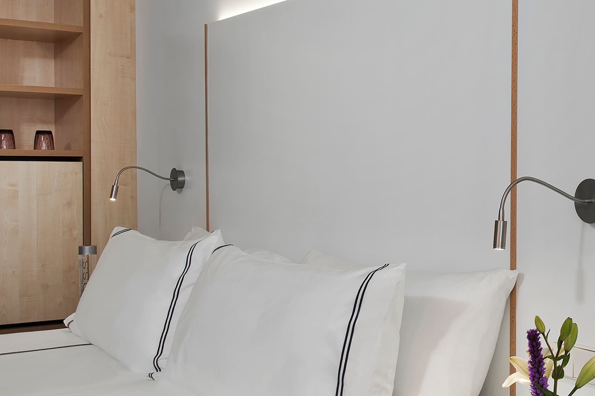 a bed with white sheets and a white nightstand