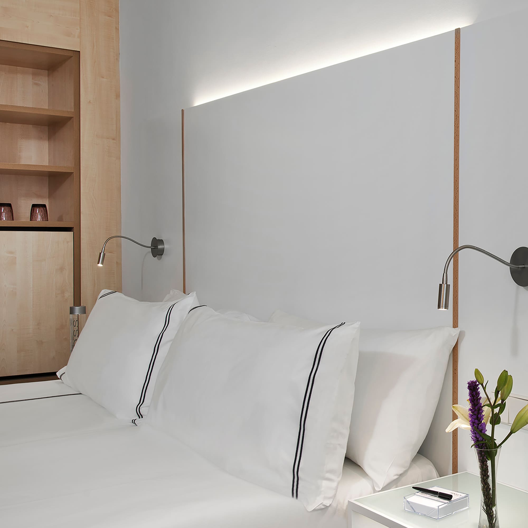 a bed with white sheets and a white nightstand