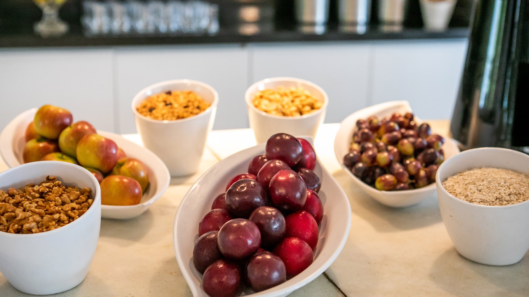 Healthy breakfast bar with fresh apples, plums, grapes, walnuts, granola, and oats.