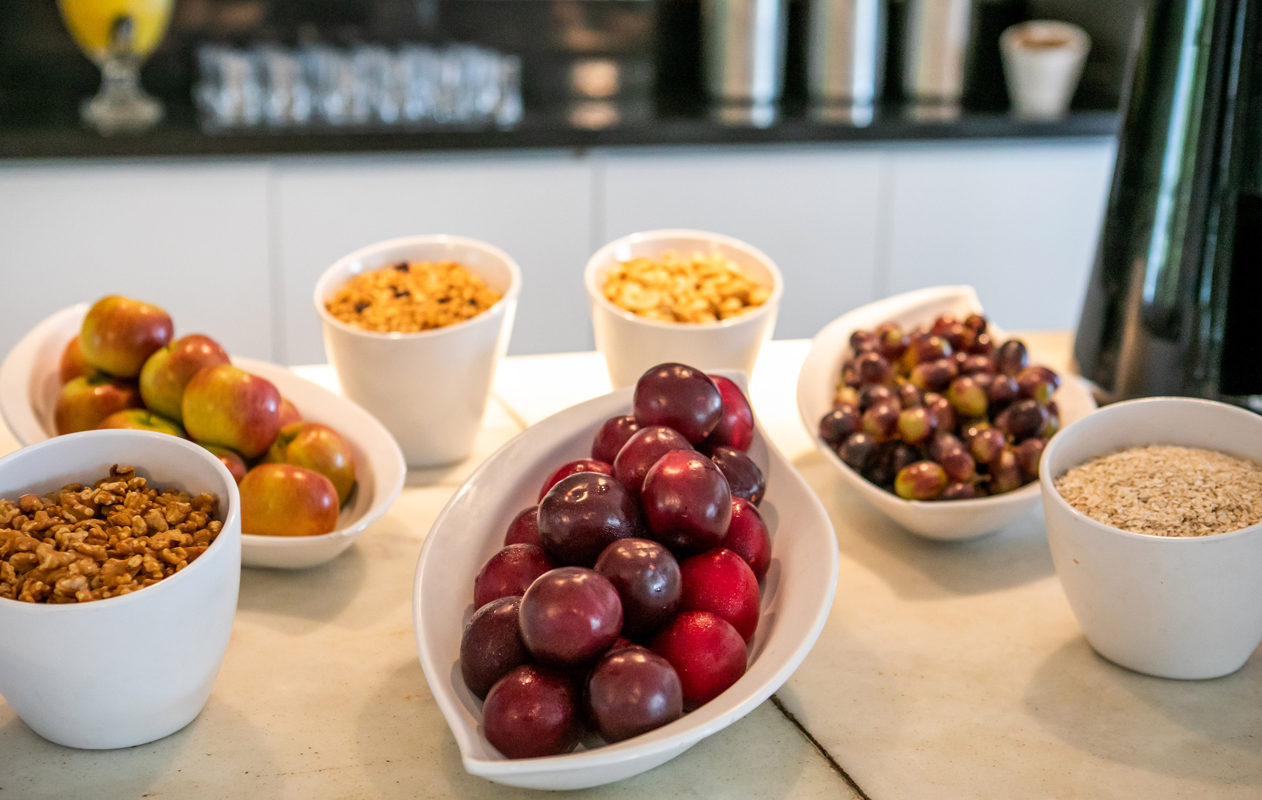 Healthy breakfast bar with fresh apples, plums, grapes, walnuts, granola, and oats.