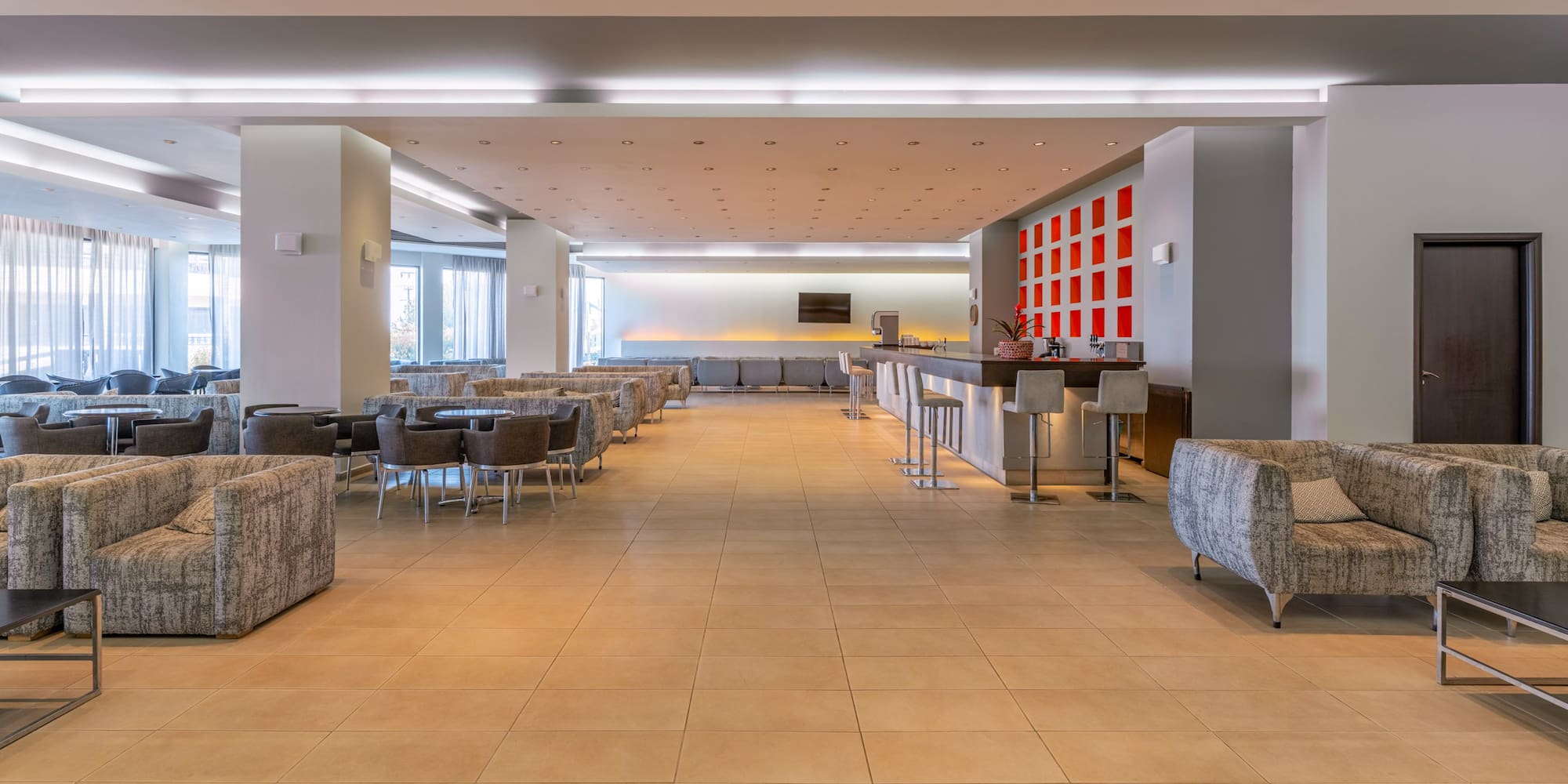 Spacious hotel lounge with modern bar, comfortable seating, and bright lighting.