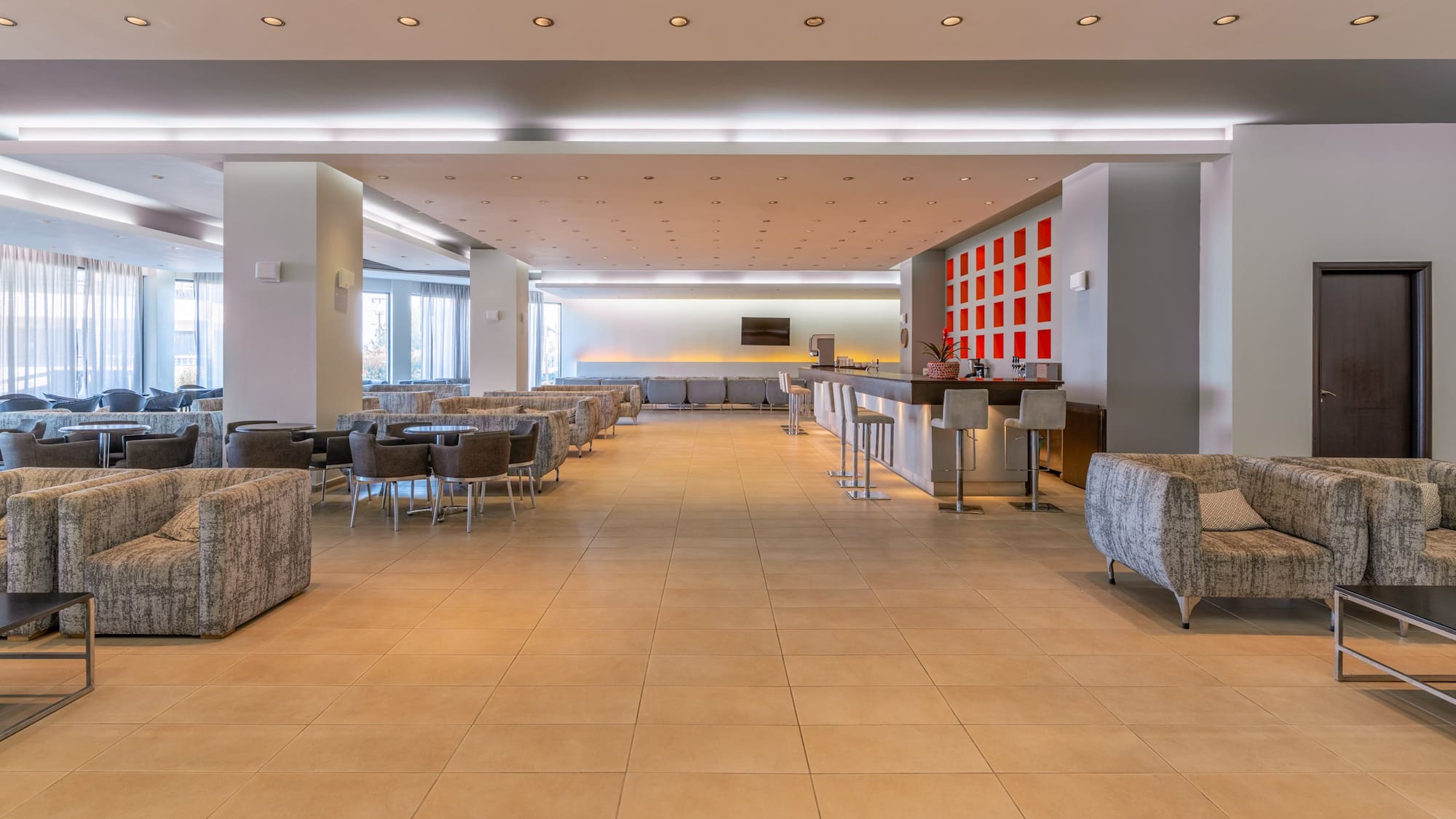 Spacious hotel lounge with modern bar, comfortable seating, and bright lighting.