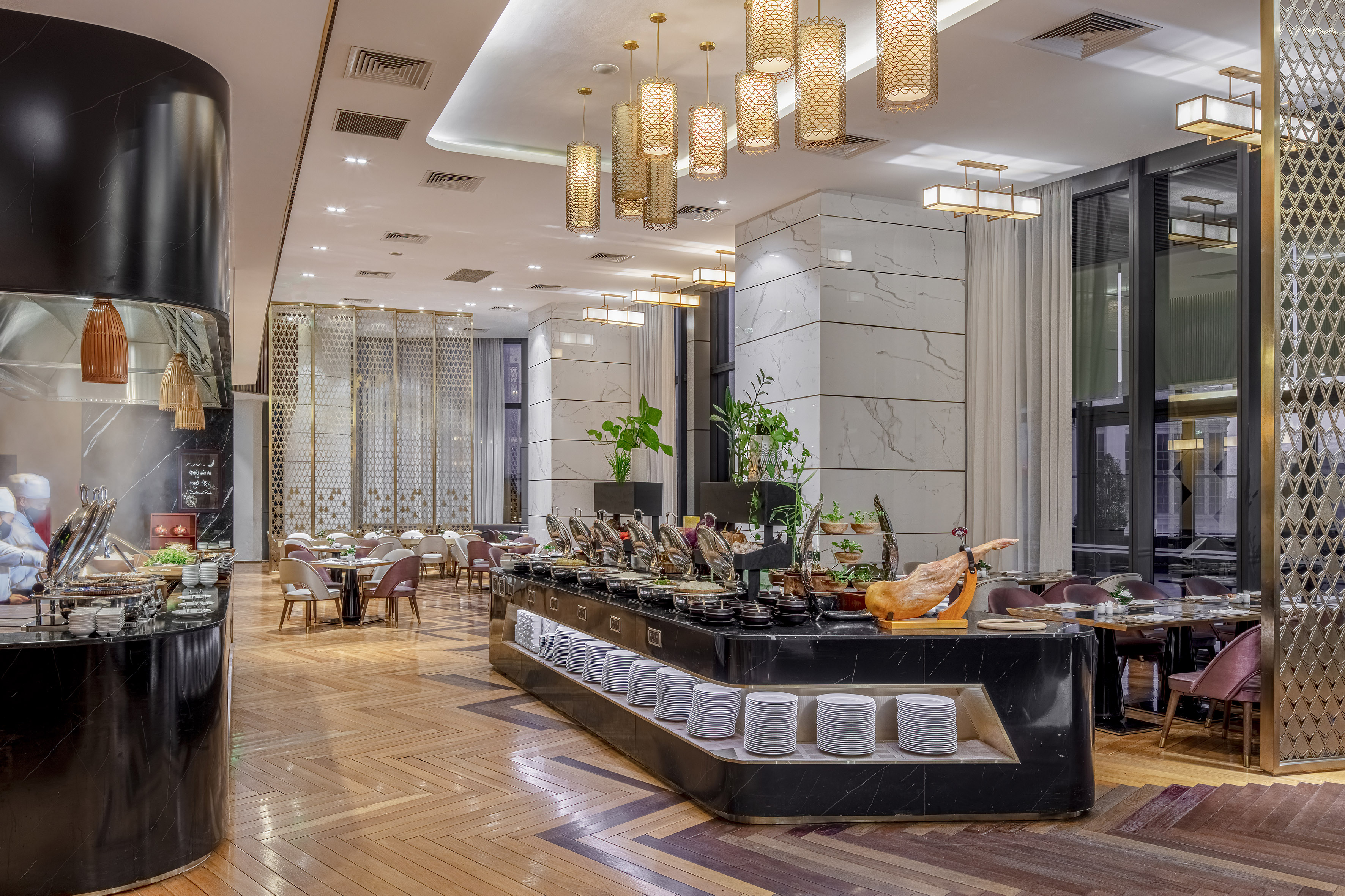 Luxury hotel buffet restaurant with golden lights, marble columns, and wood floor.