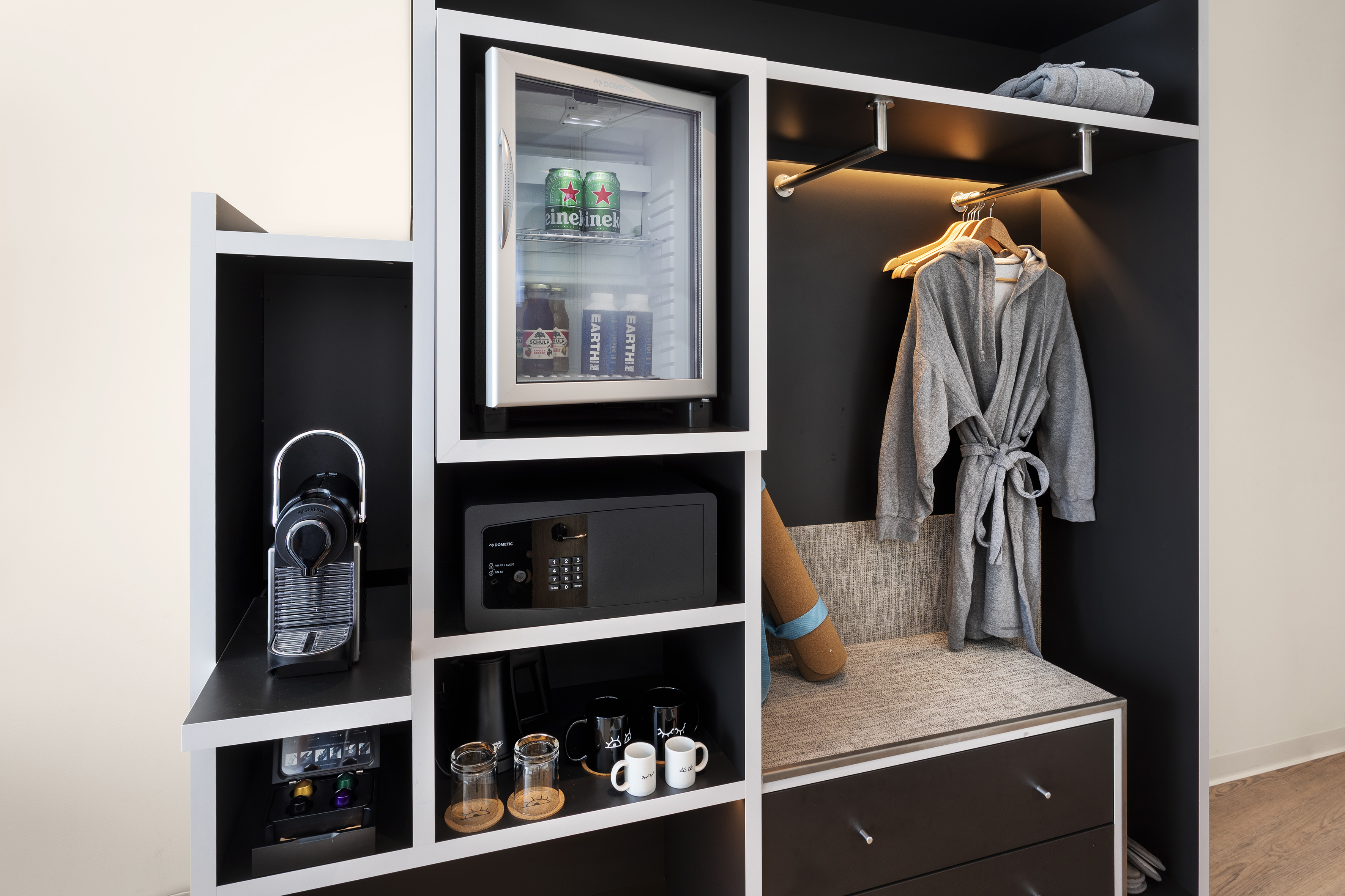 Hotel room wardrobe with Nespresso, minibar, safe, and bathrobe.