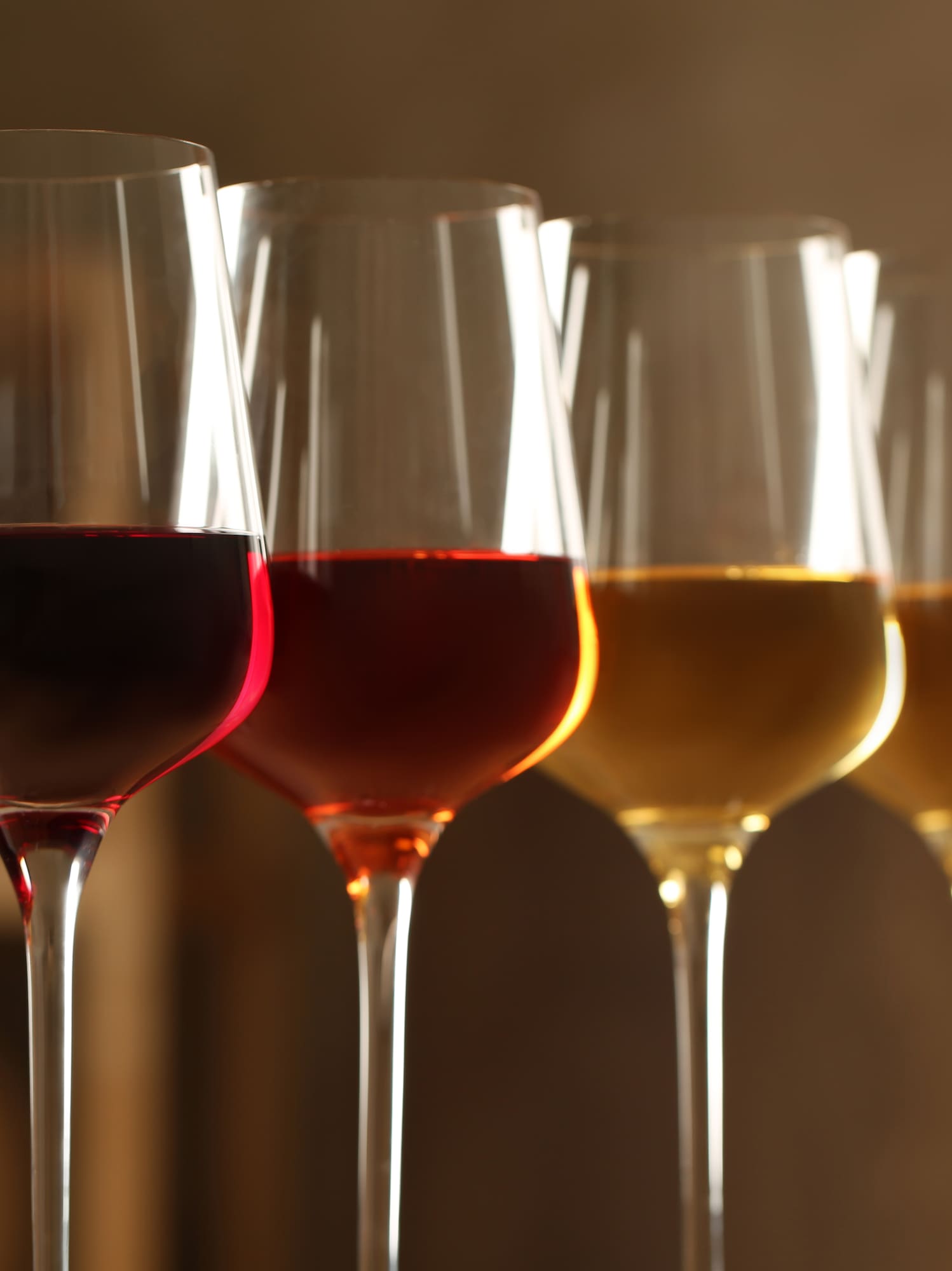 Row of wine glasses with red, rosé, and white wine for tasting.