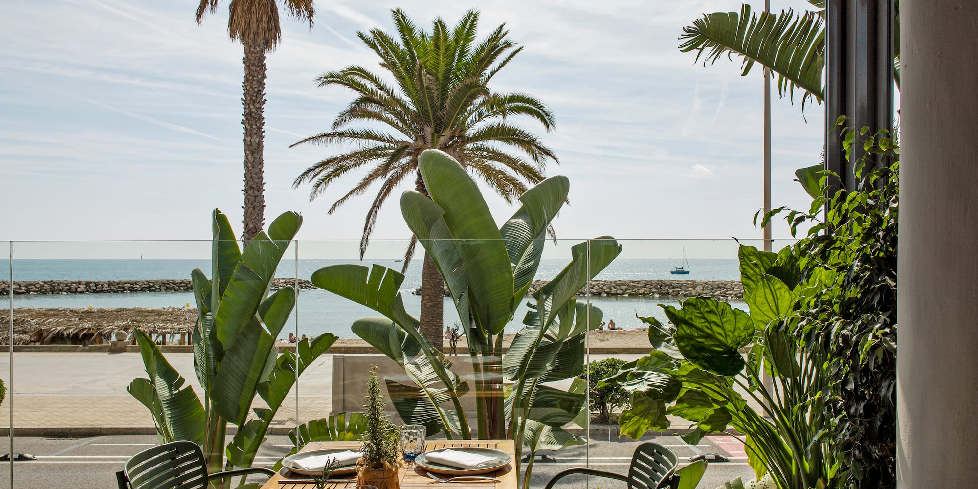 a table with plates and chairs outside with a view of the ocean