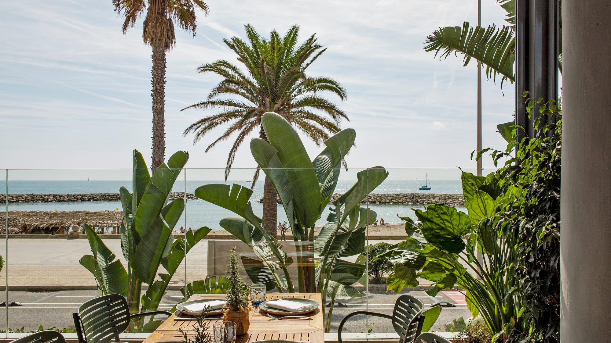 a table with plates and chairs outside with a view of the ocean