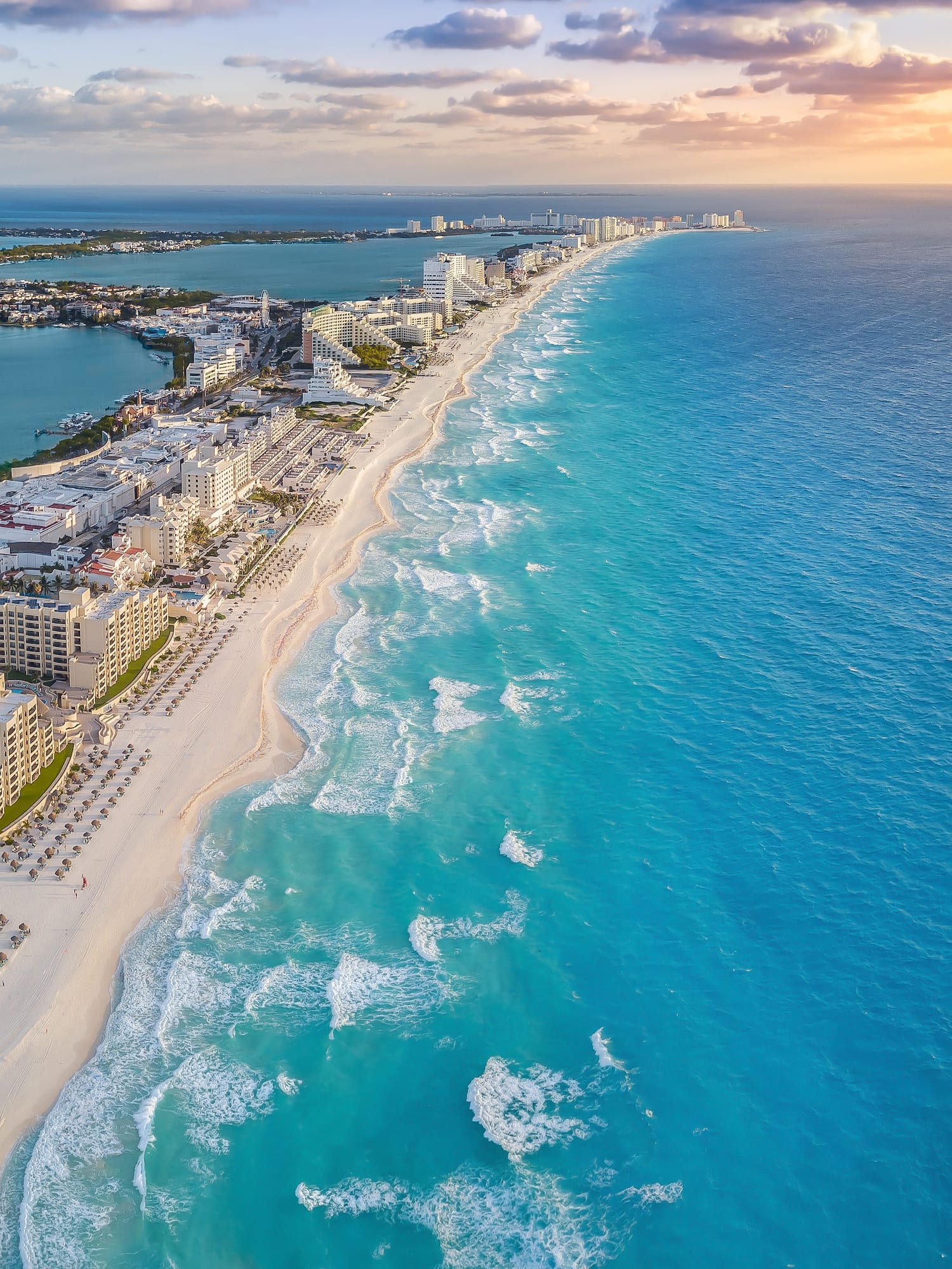 Cancun turquoise beach, white sand, resorts, and ocean at sunset.
