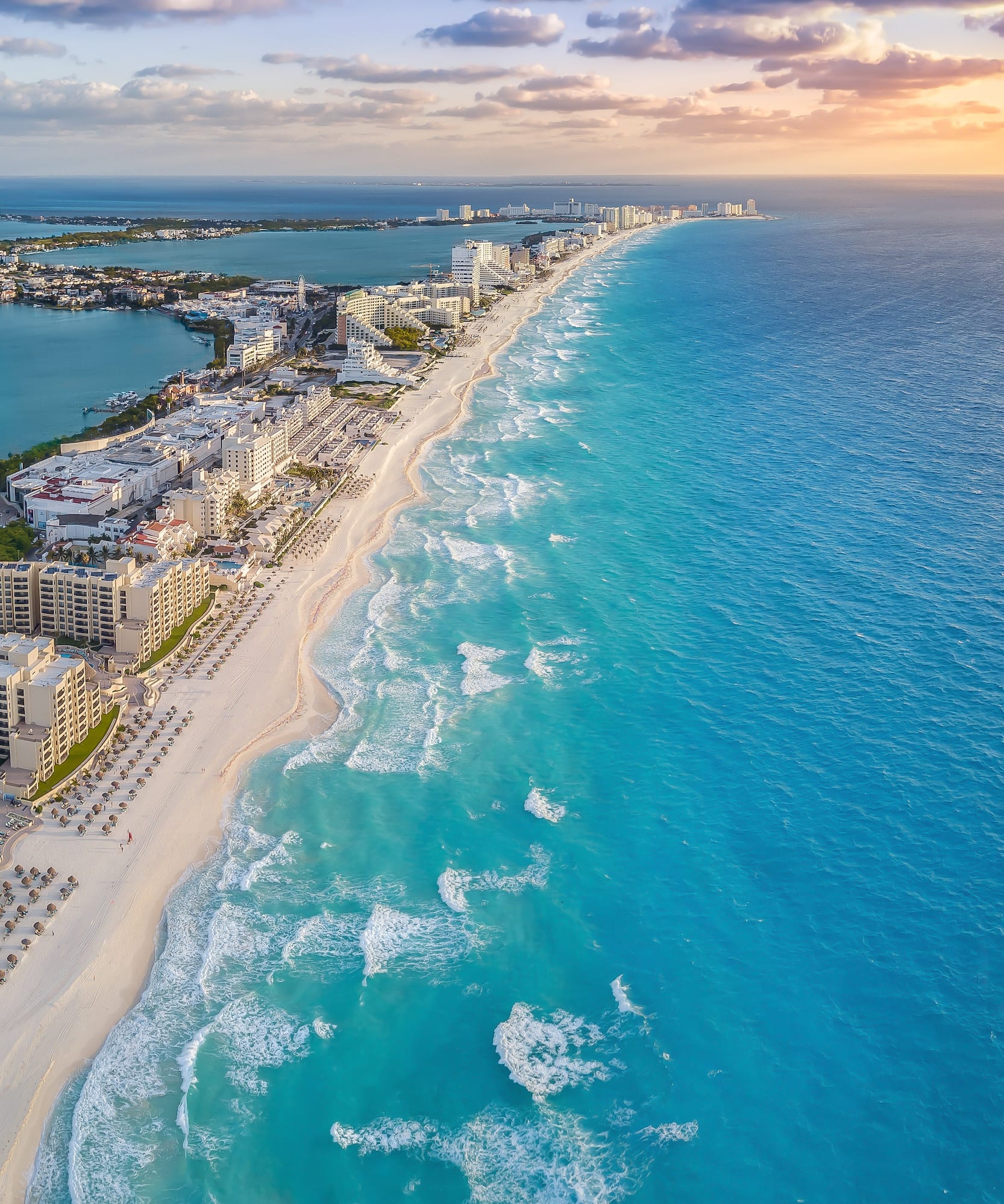 Cancun turquoise beach, white sand, resorts, and ocean at sunset.