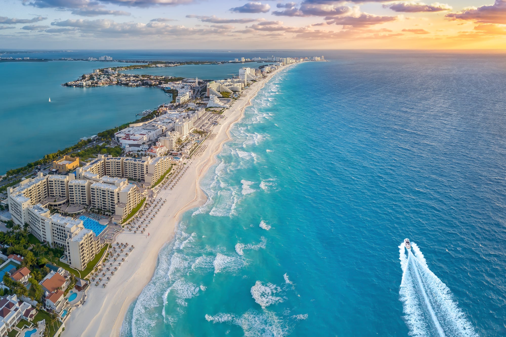 Cancun turquoise beach, white sand, resorts, and ocean at sunset.