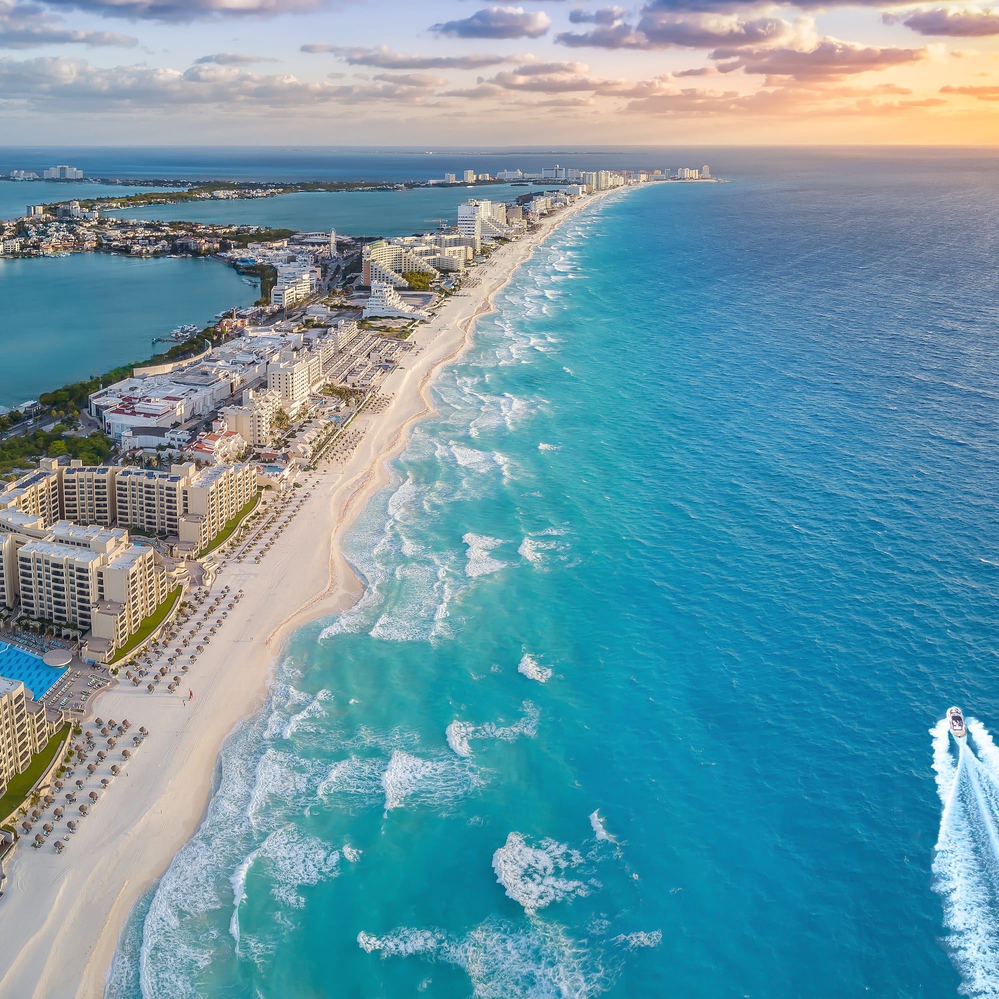 Cancun turquoise beach, white sand, resorts, and ocean at sunset.