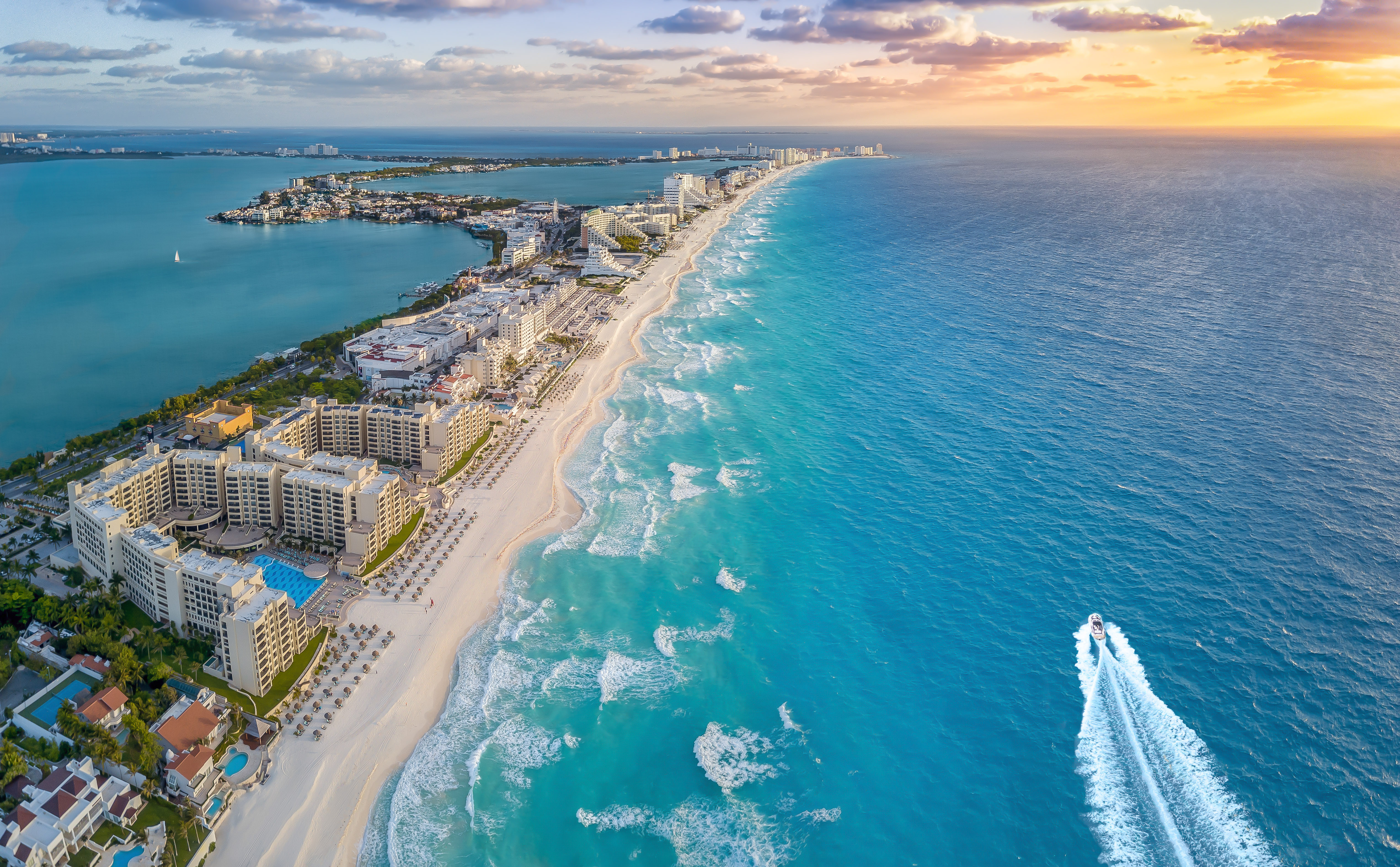 Cancun turquoise beach, white sand, resorts, and ocean at sunset.