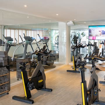 a room with exercise bikes and a large screen