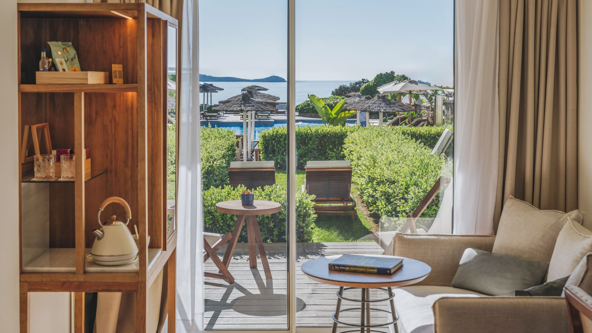 Resort suite with sea view balcony, pool, and lush garden.
