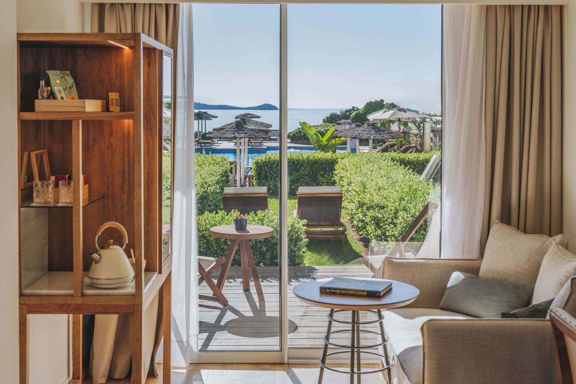 Resort suite with sea view balcony, pool, and lush garden.