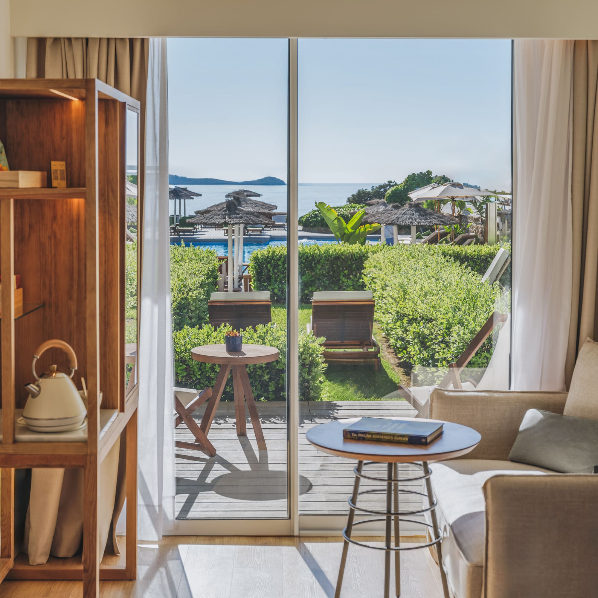 Resort suite with sea view balcony, pool, and lush garden.