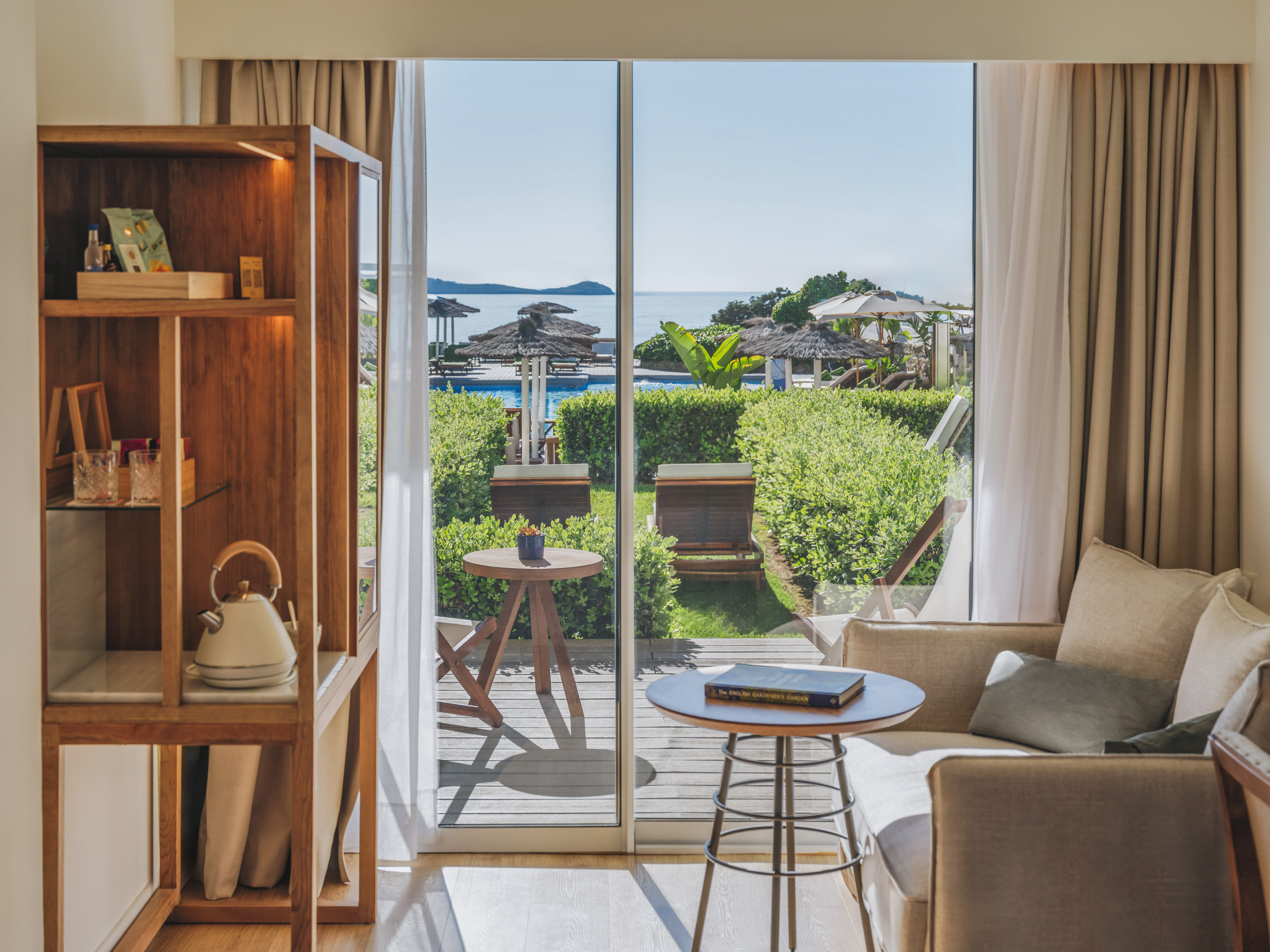 Resort suite with sea view balcony, pool, and lush garden.