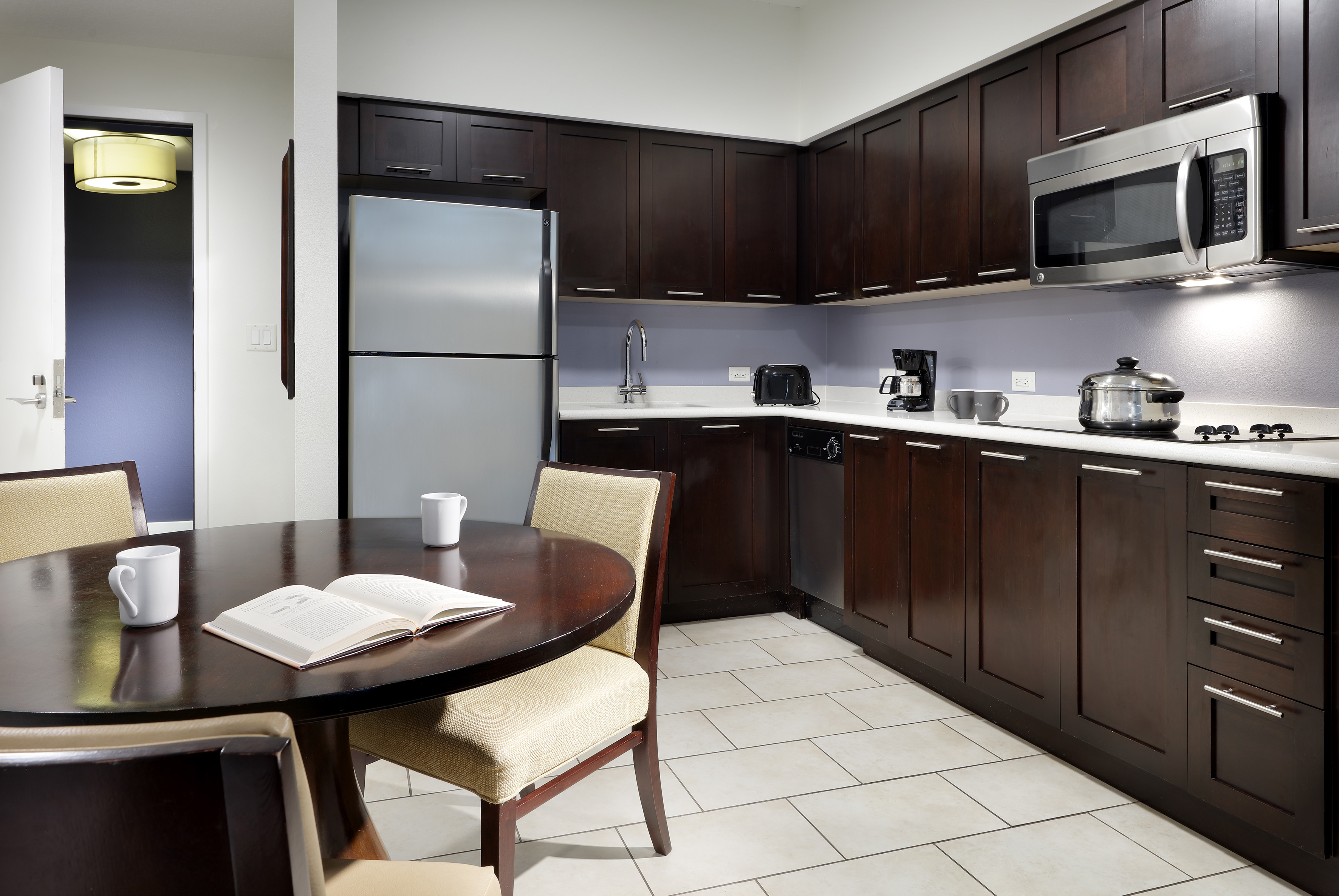 Modern kitchen with dark cabinets, stainless steel appliances, and dining table.