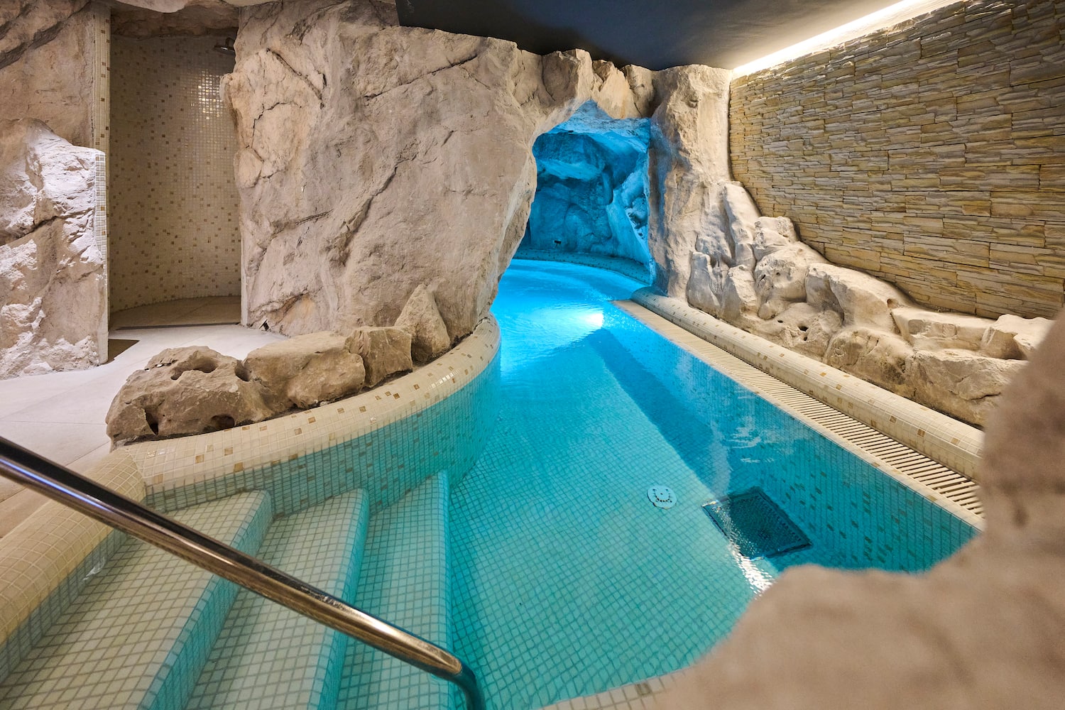 a indoor pool with a rock wall and stairs