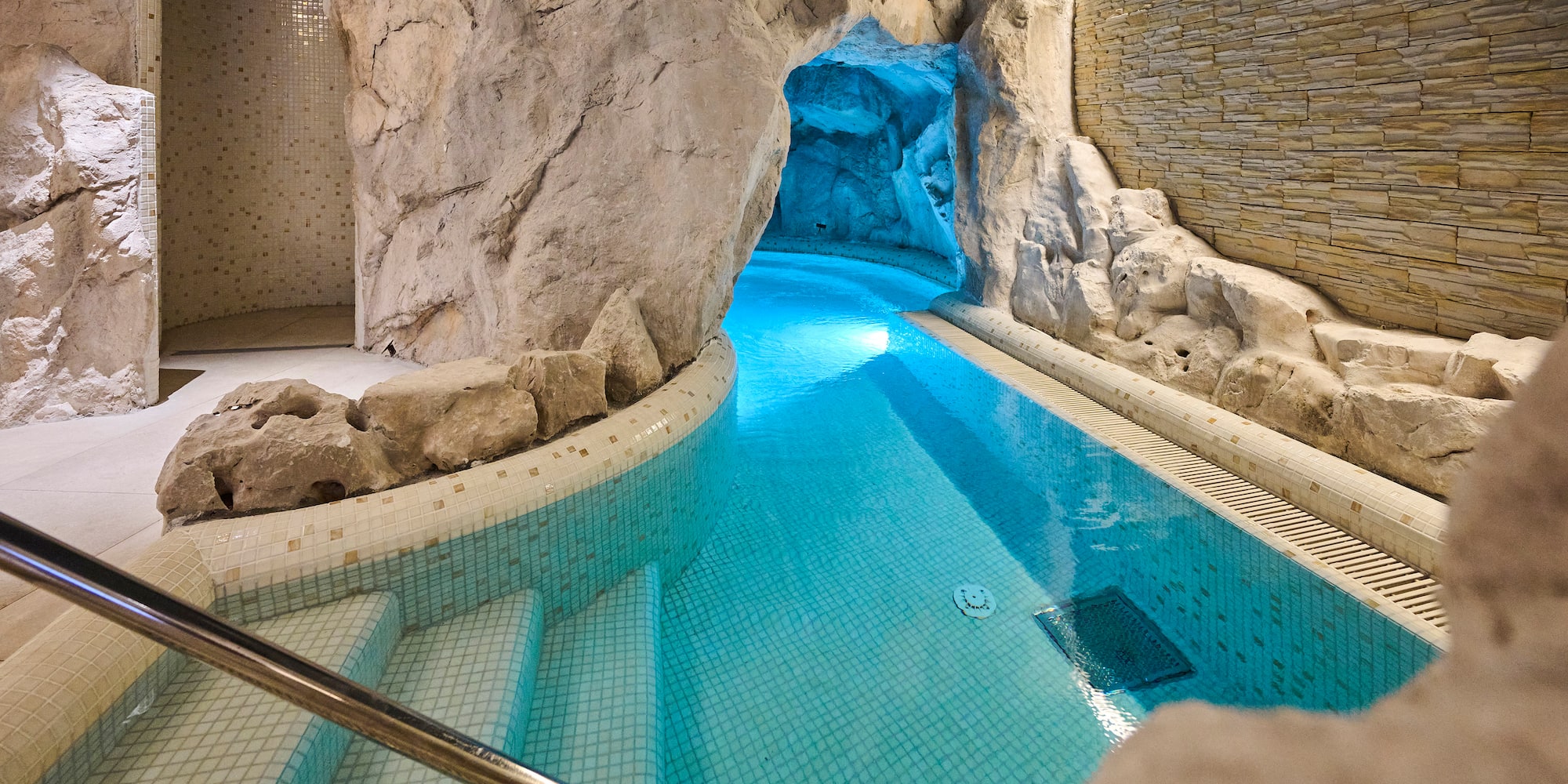 a indoor pool with a rock wall and stairs