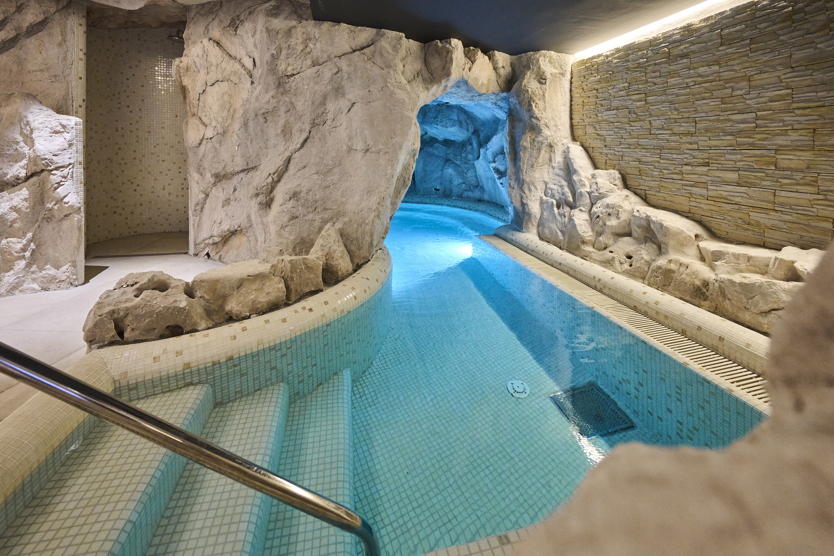 a indoor pool with a rock wall and stairs