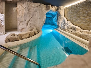 a indoor pool with a rock wall and stairs