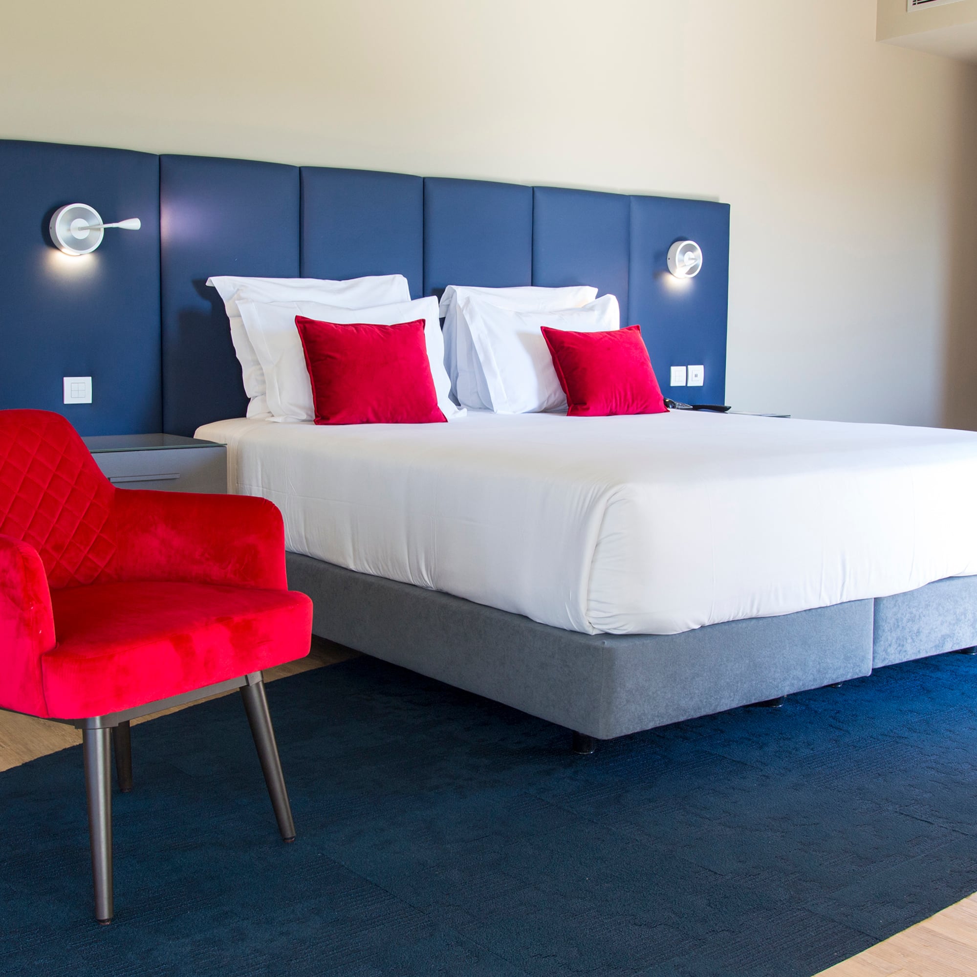 a bed with red pillows and a chair in a room