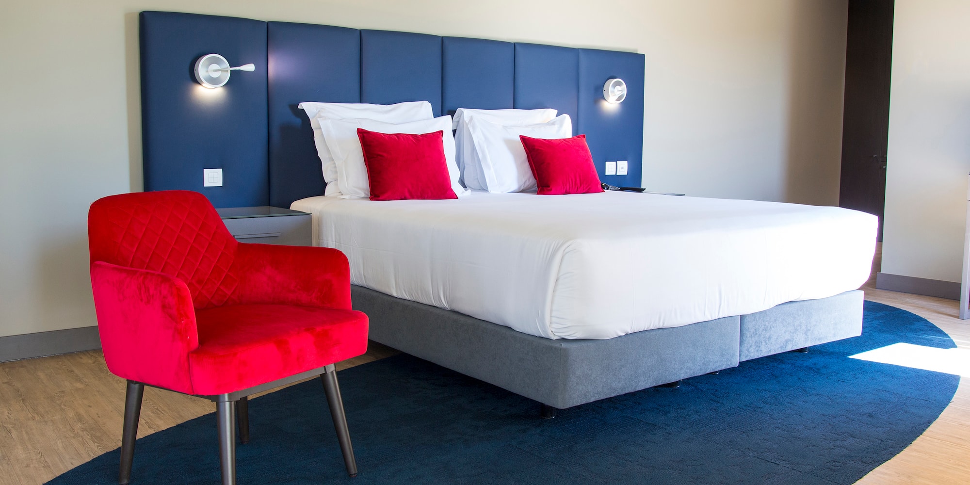 a bed with red pillows and a chair in a room