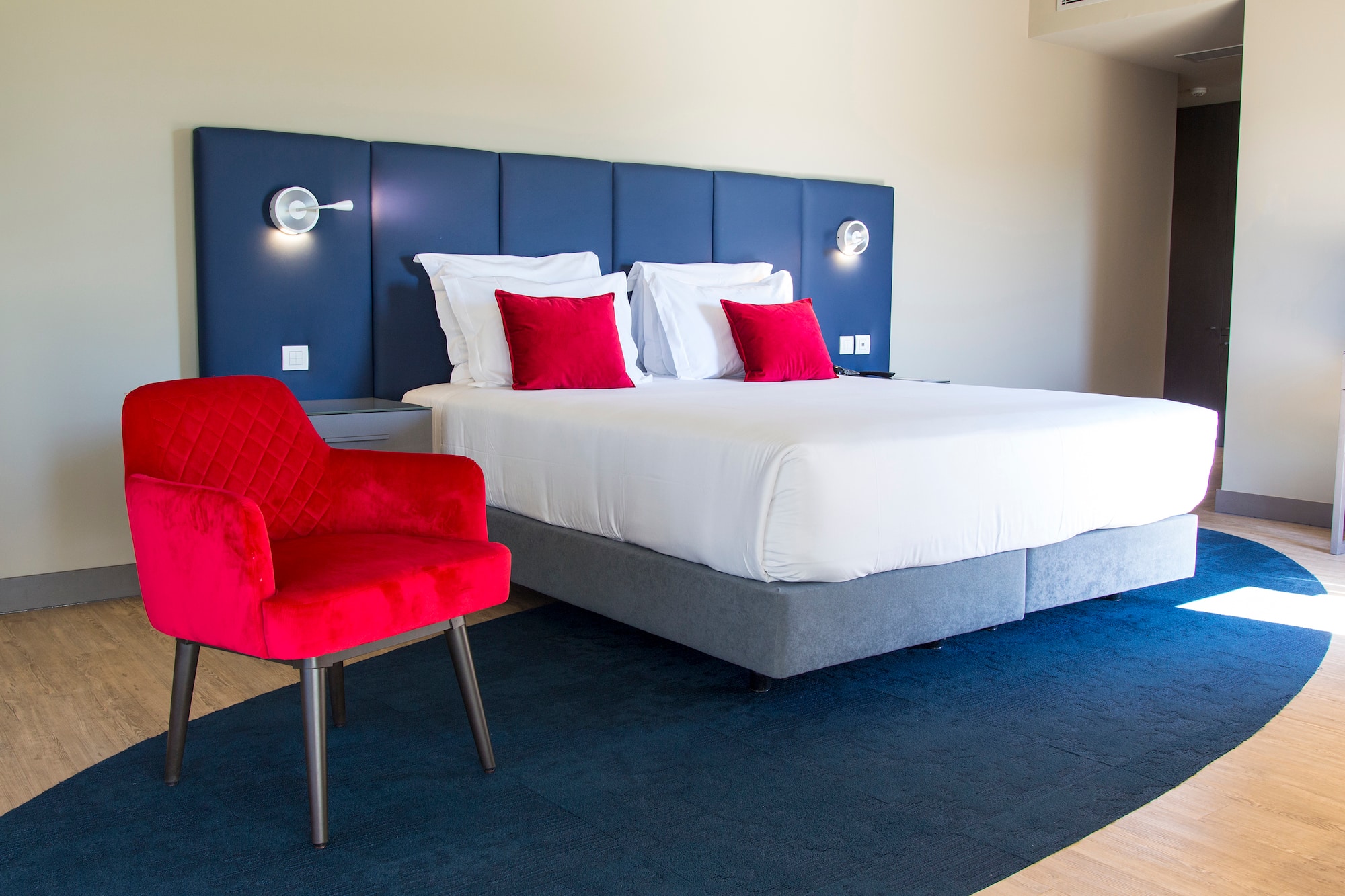 a bed with red pillows and a chair in a room