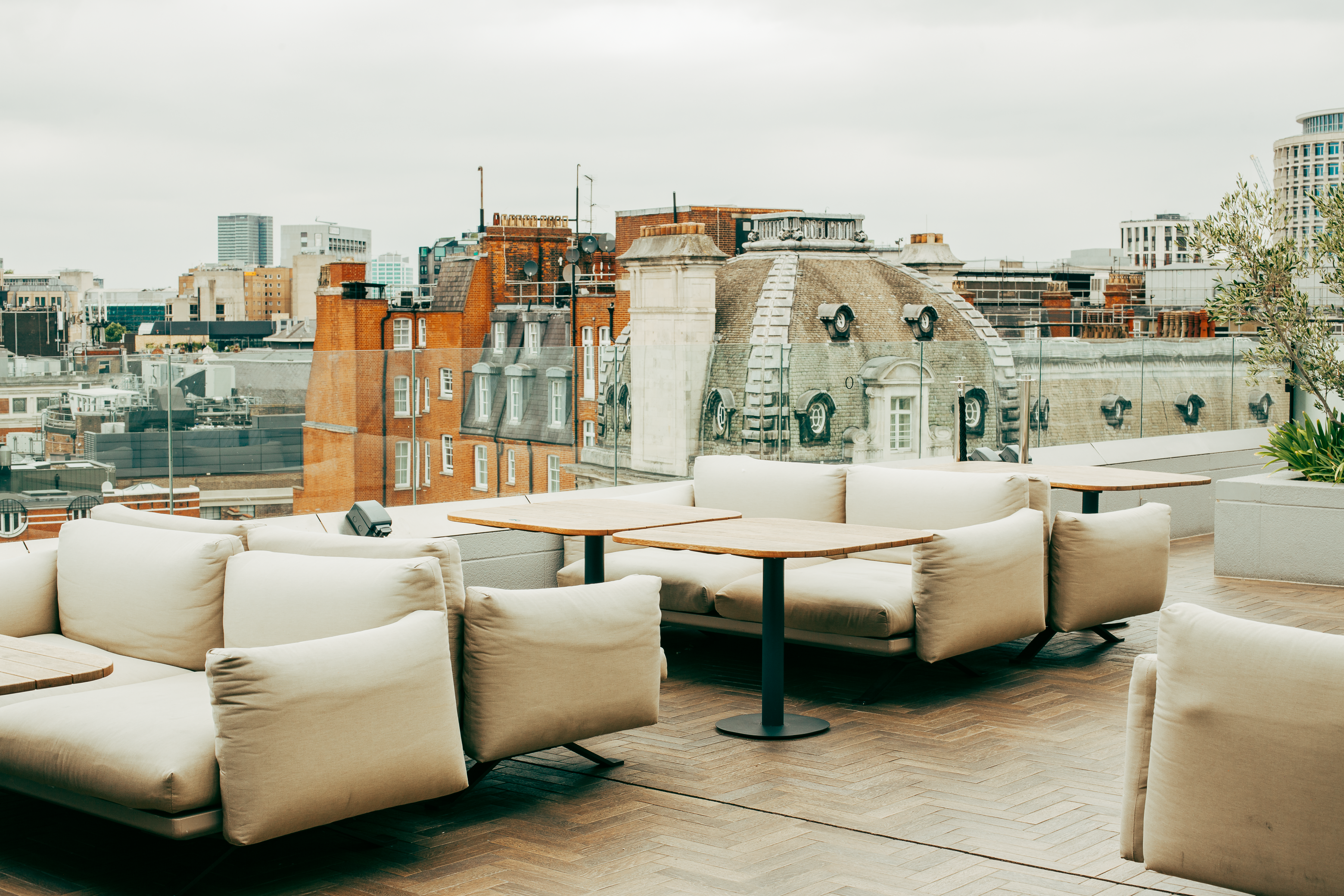 Rooftop terrace with outdoor sofas, tables, and historic urban cityscape.