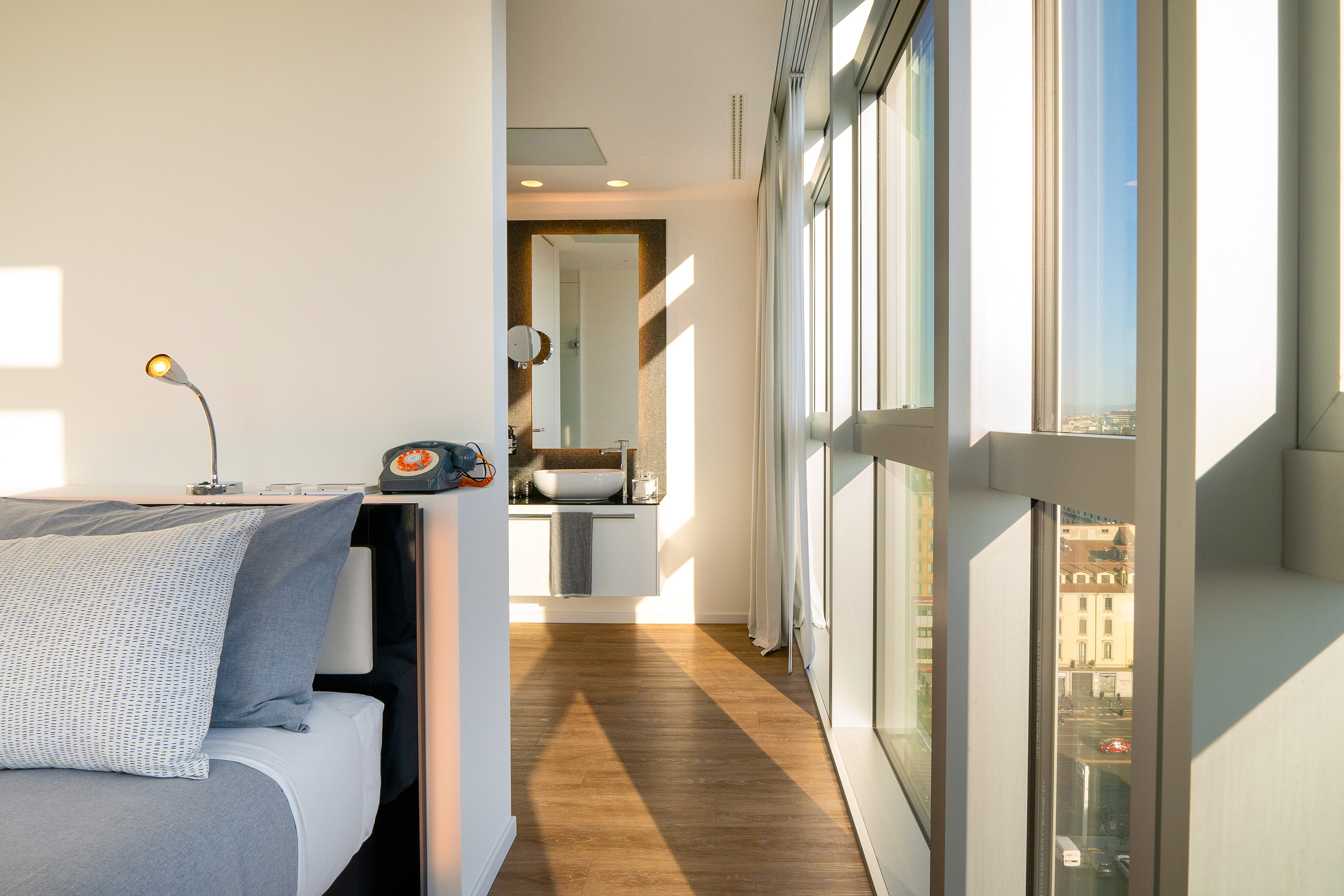 Modern bedroom suite with city view, large windows, and en-suite bathroom.