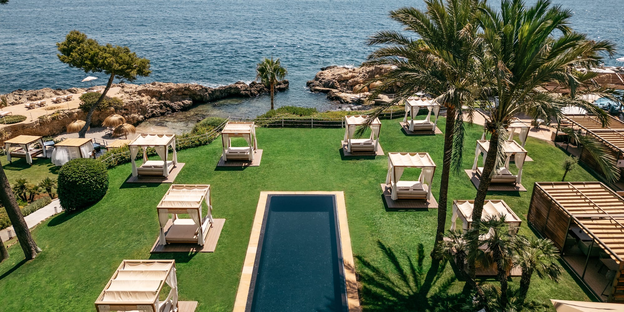 a pool with lounge chairs and palm trees by the water.