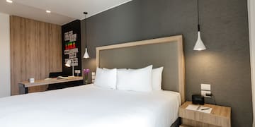 a bed with white sheets and a wood headboard