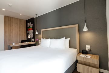 a bed with white sheets and a wood headboard