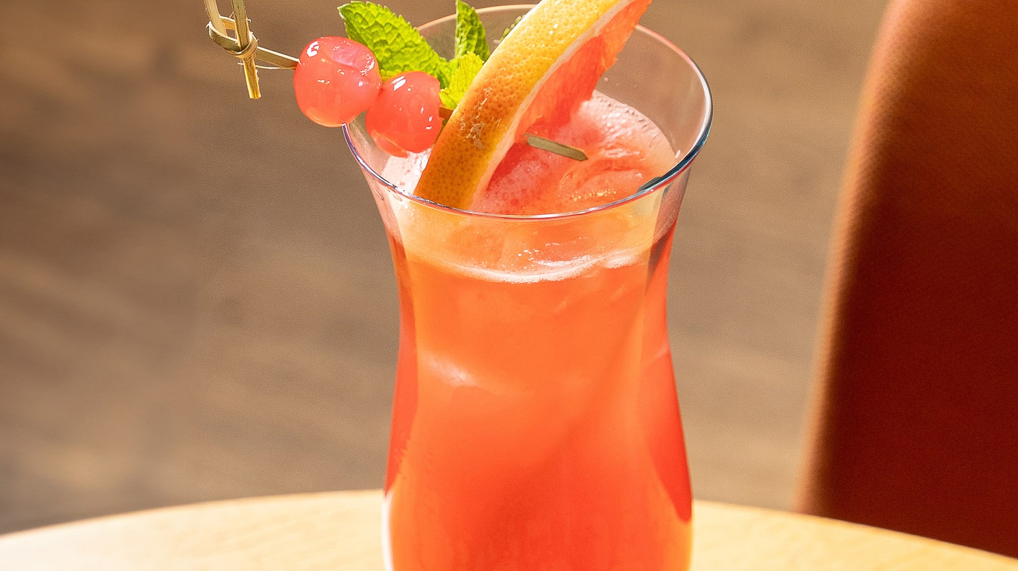 a glass of pink drink with fruit and mint